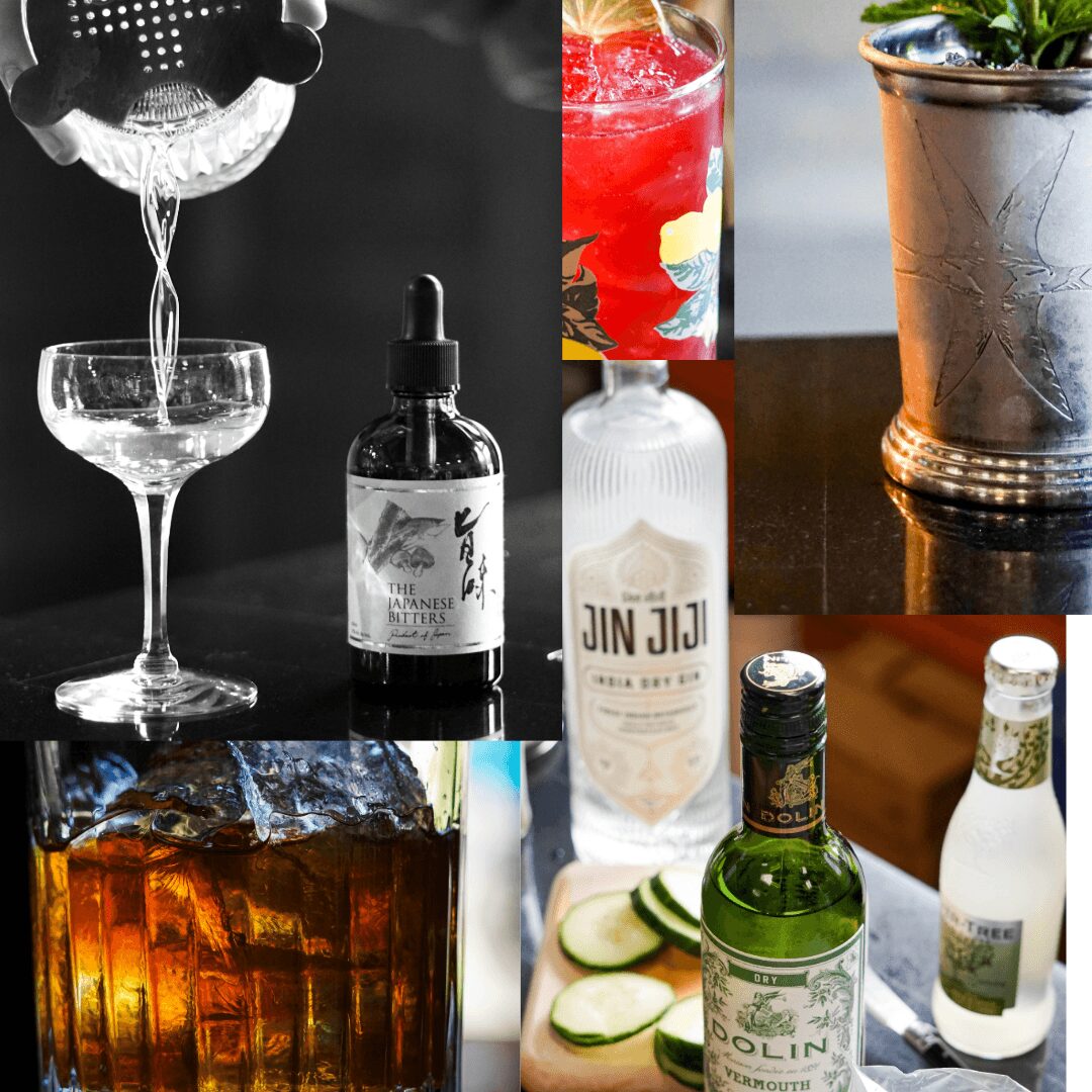 Assorted drinks including a cocktail, juice, soda, and bottled beverages on a table, with a potted plant in the background.