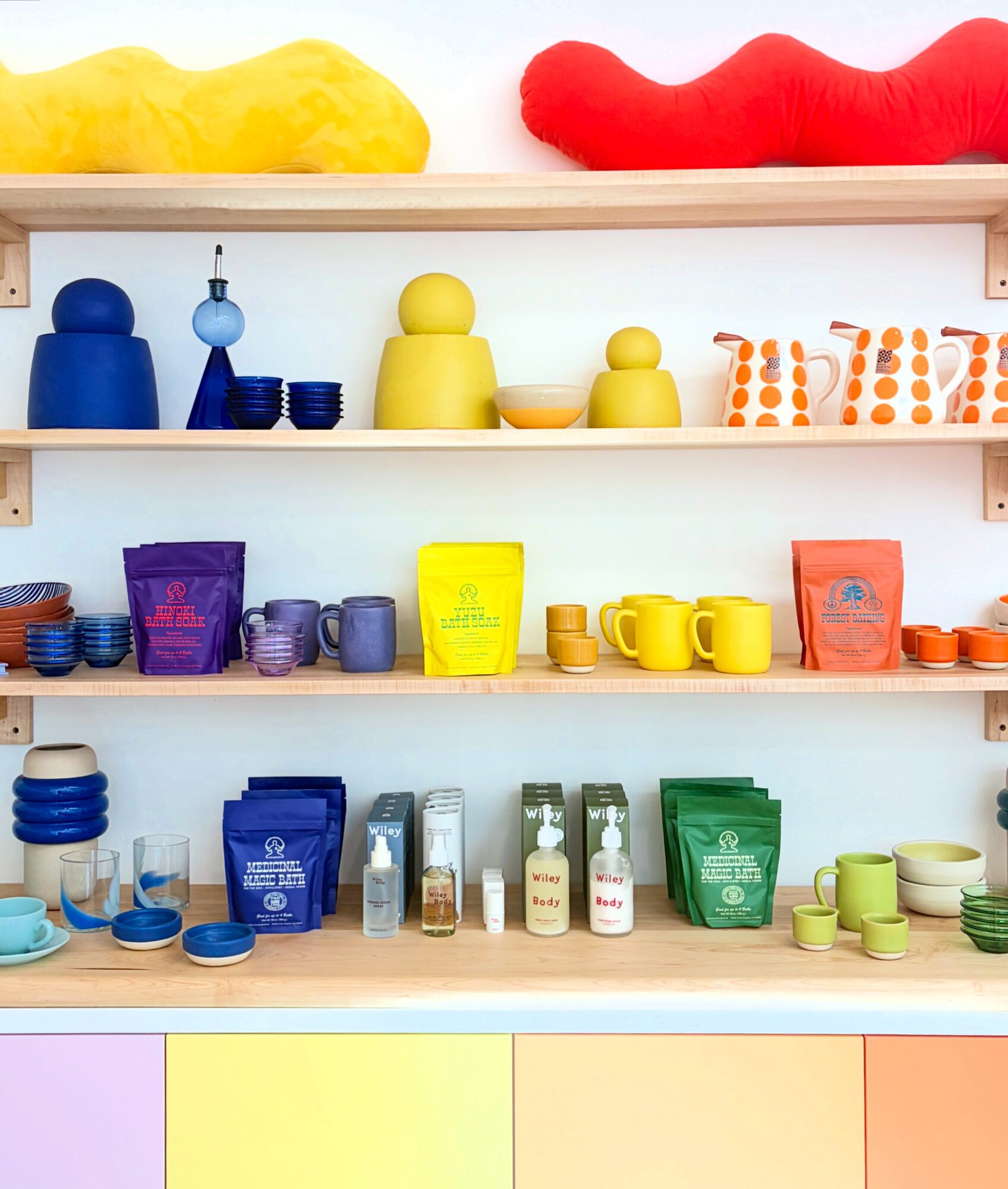 Shelves with colorful toys, cups, and packages arranged in rows, with plush toys on top. Bright, organized display.
