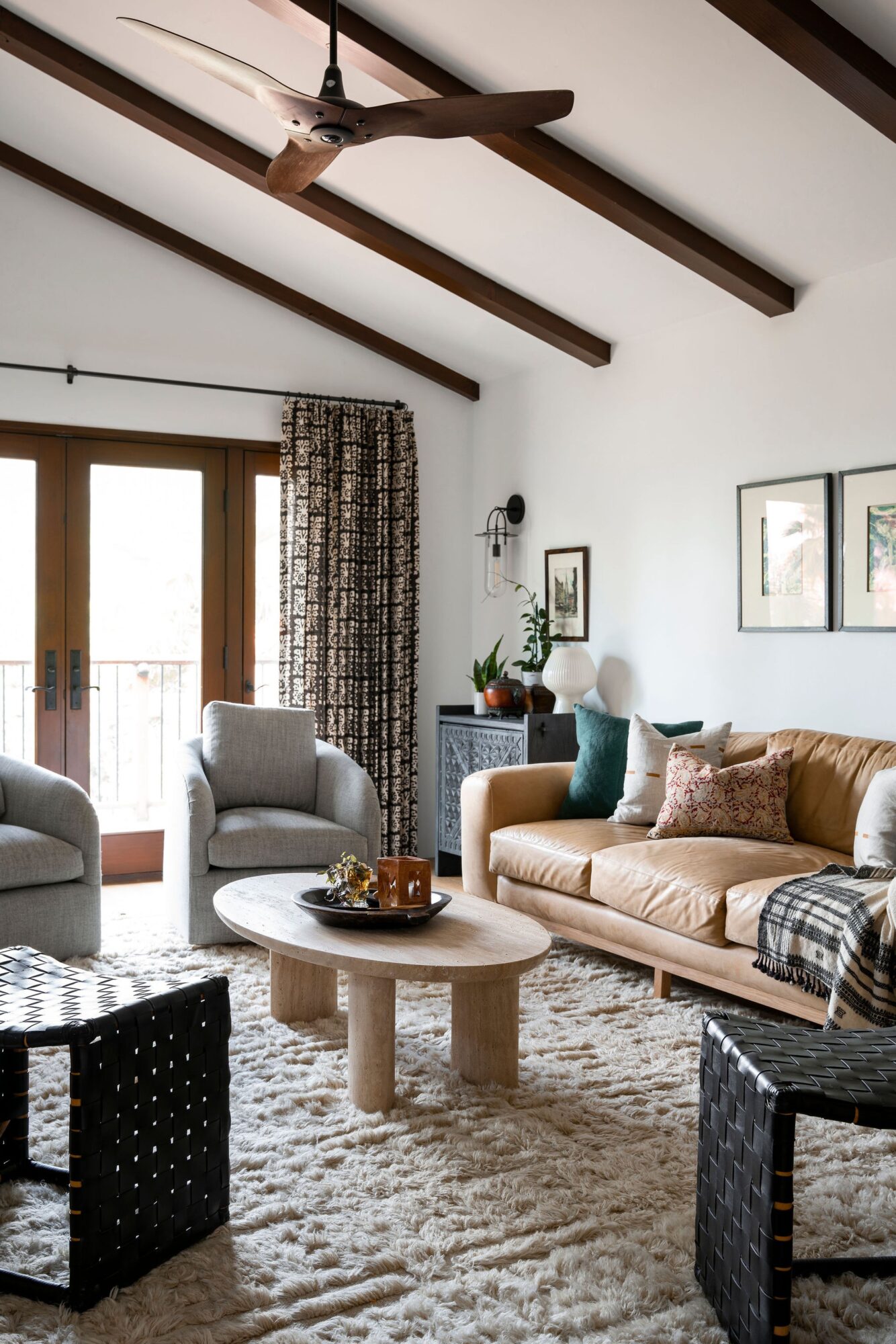 Living room with beige sofa, armchairs, round coffee table, and large windows with curtains.