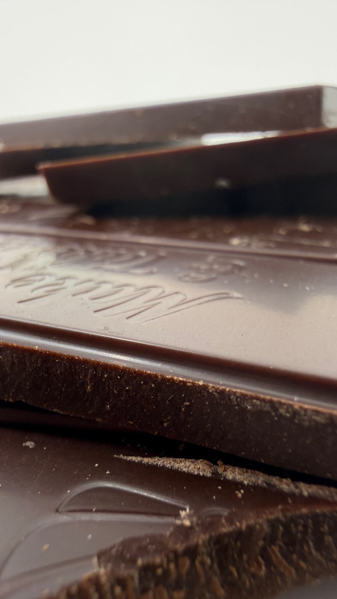 Close-up of broken chocolate pieces with textured surface and embossed text, on a flat surface.