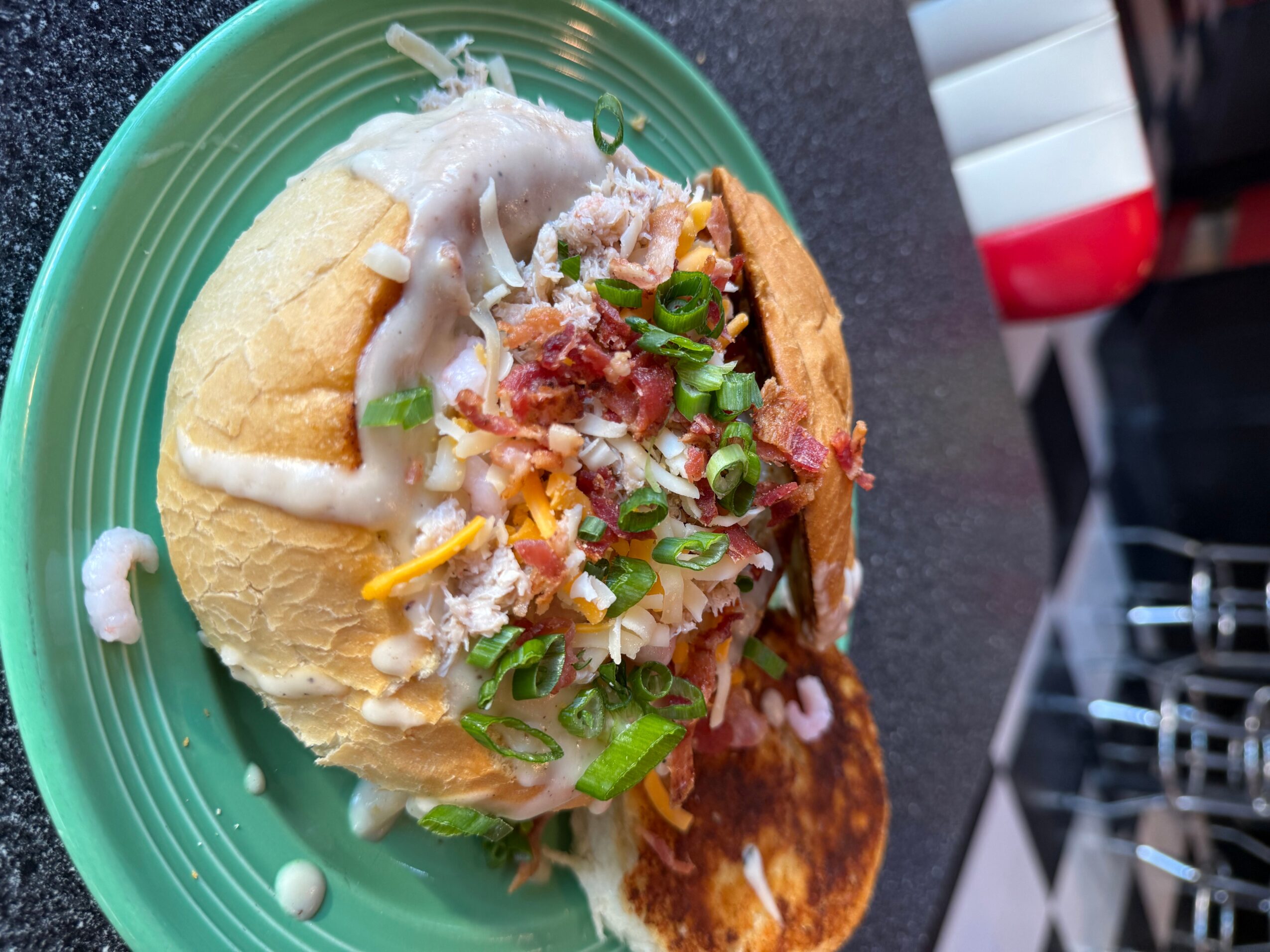 Taco with meat, cheese, lettuce, and sauce on a green plate, viewed from the side.
