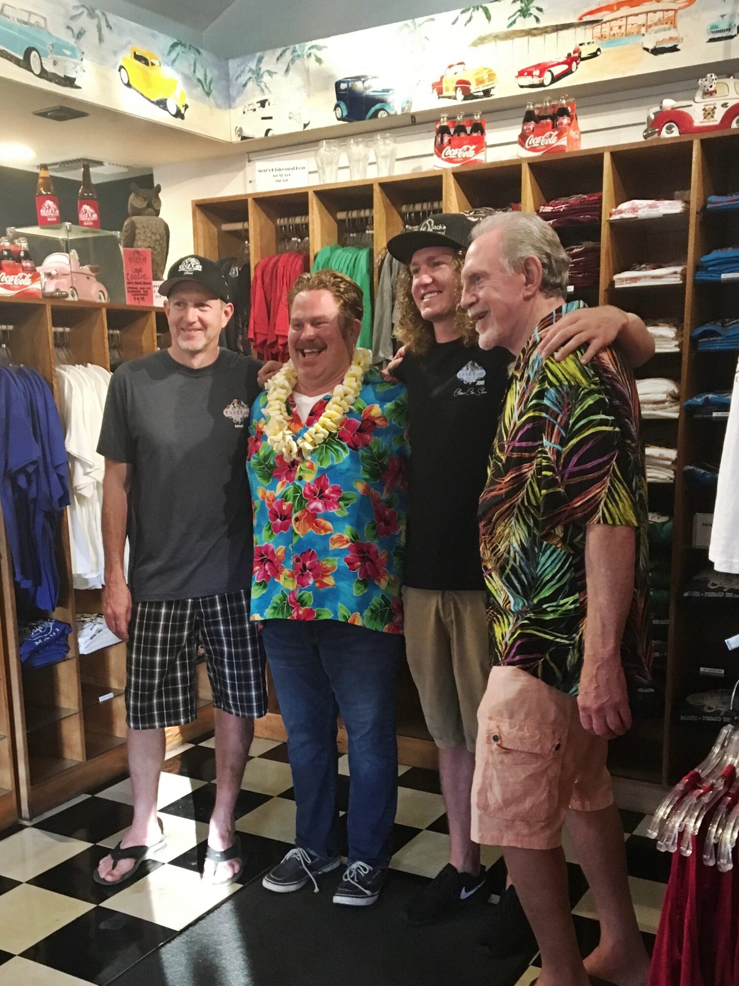 Four people standing inside a clothing store, smiling, with shelves of hats and clothes behind them.