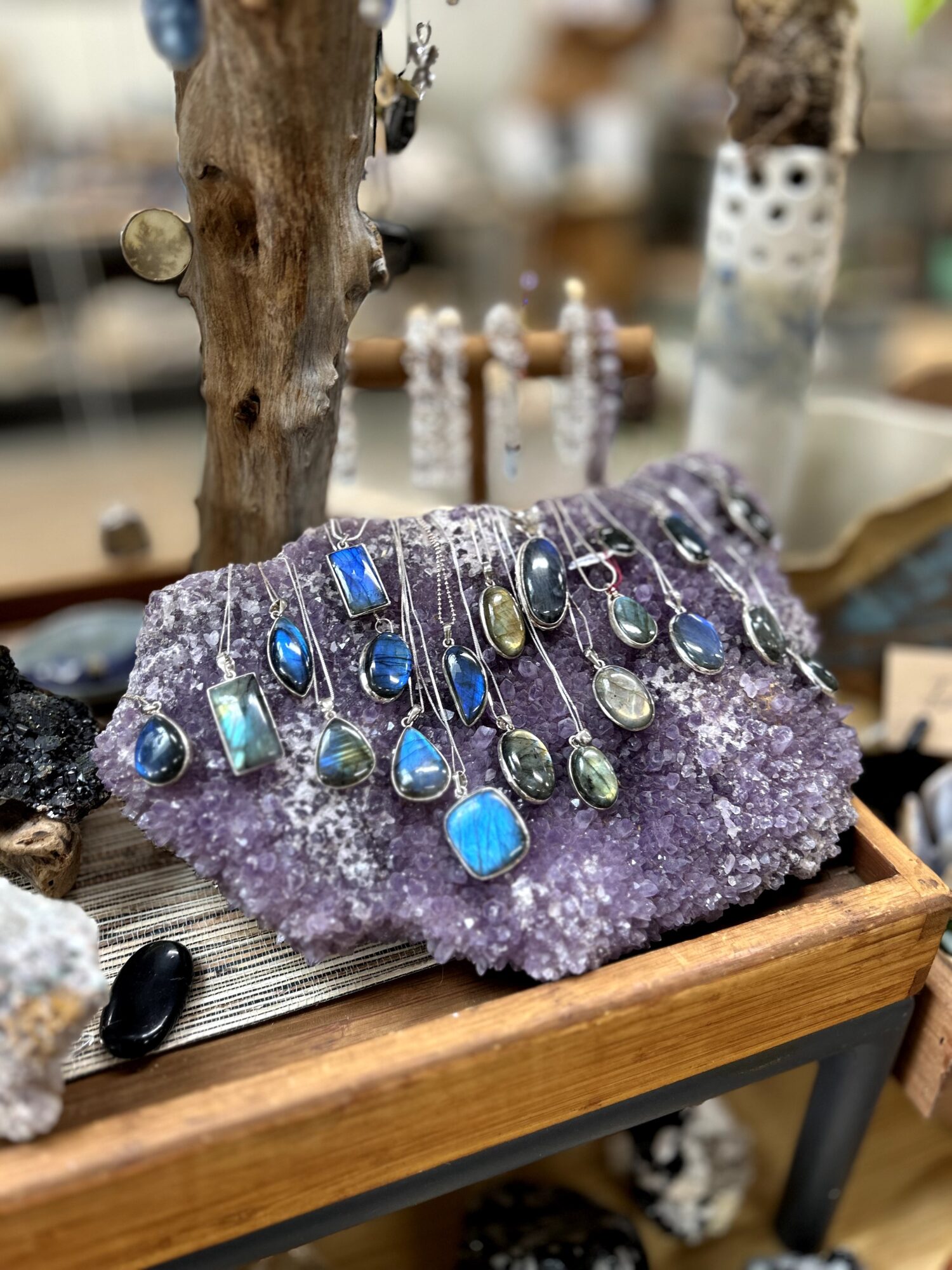 Jewelry displayed on a purple crystal, with necklaces featuring blue and green stones, in a shop setting.