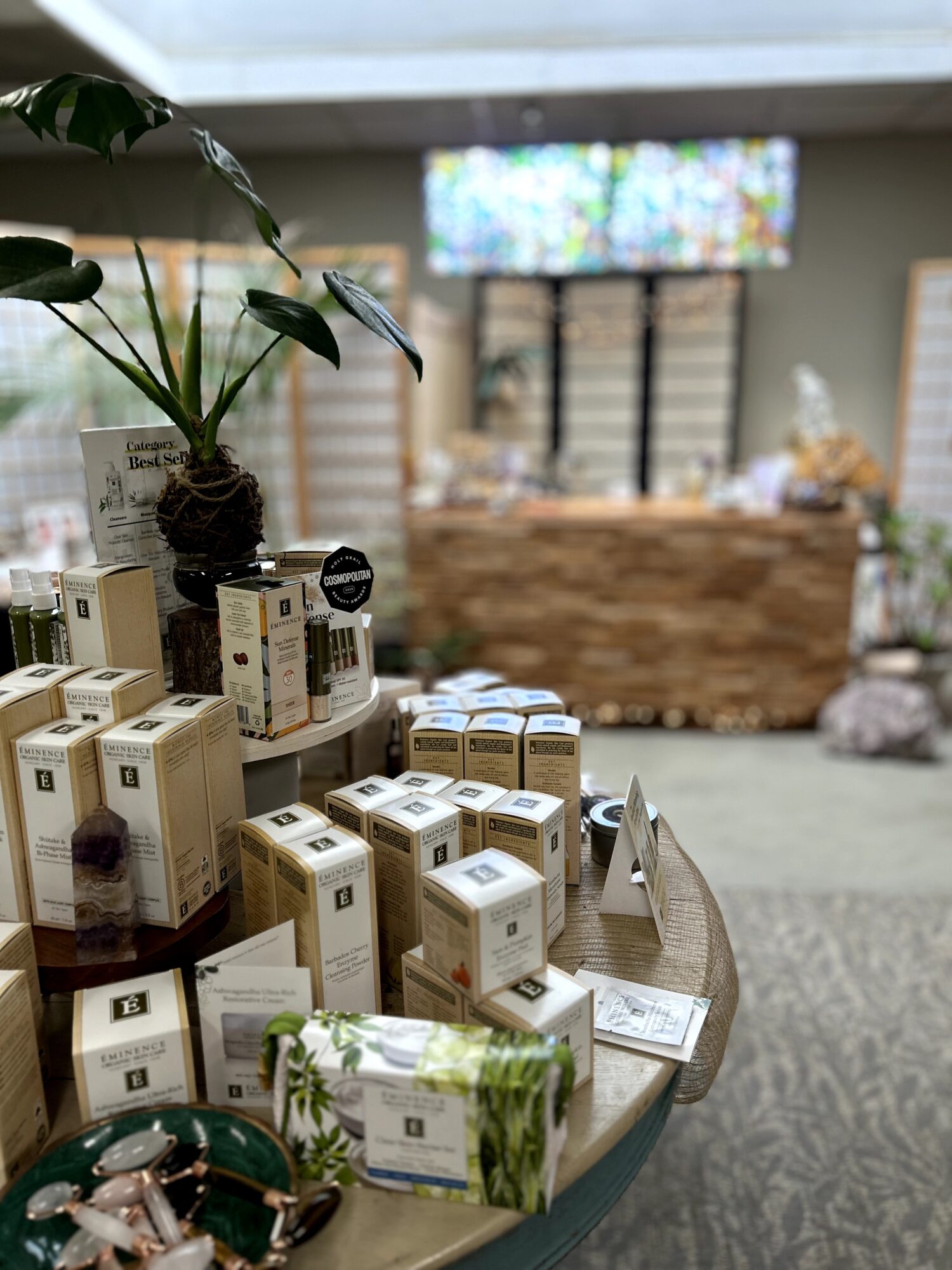 Display of various boxed products on a table with a potted plant, in a store setting with a blurred background.