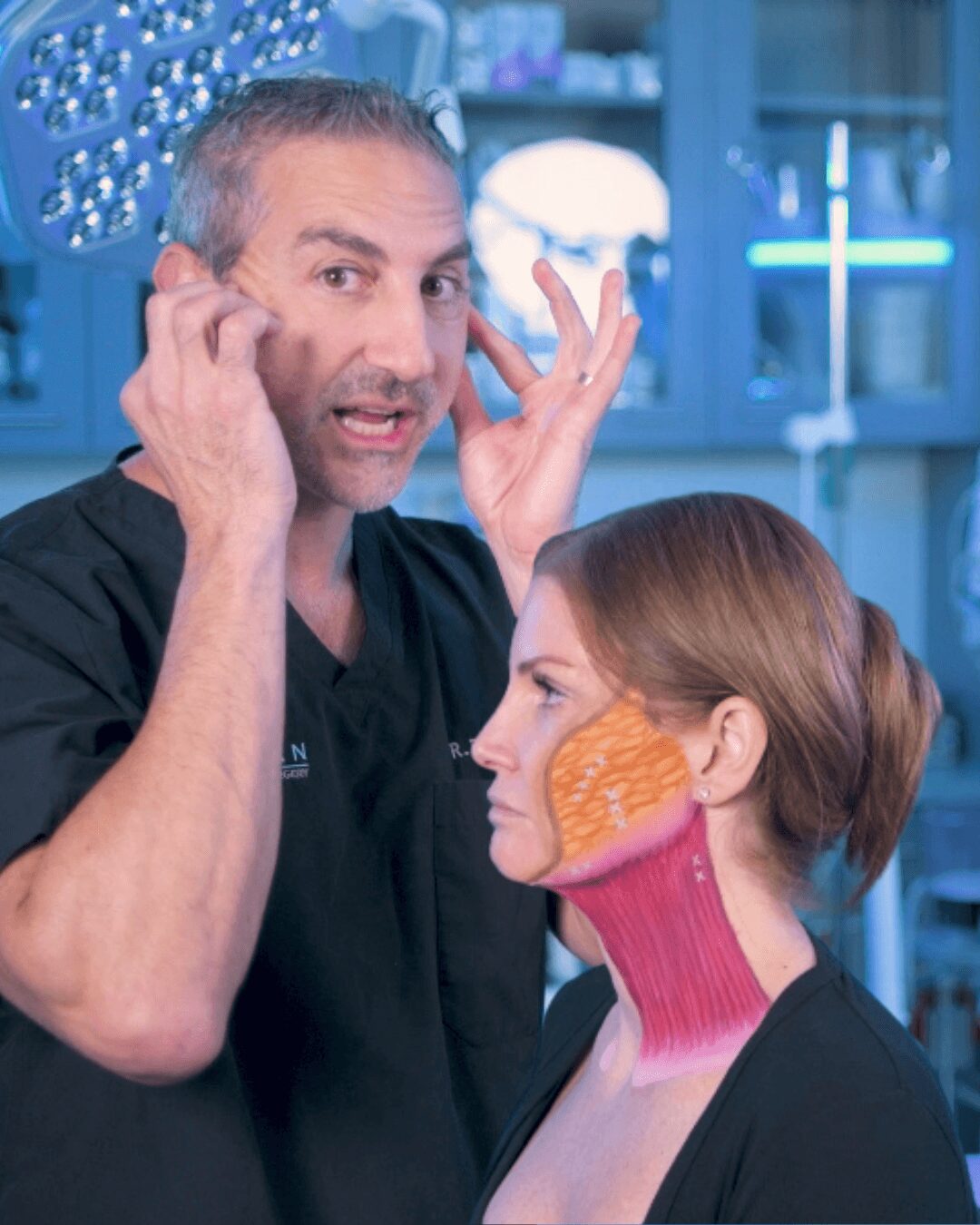 A man with gray hair and a woman with short hair are in a medical or scientific setting, with the woman having a colorful neck and face mask.