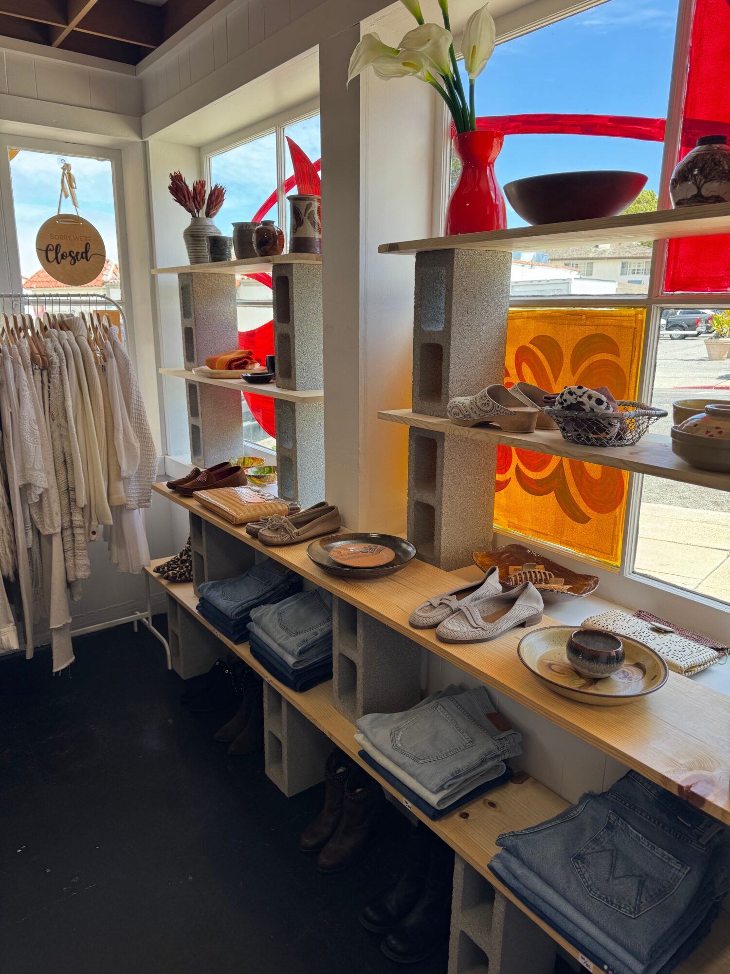 Counter with plates, napkins, and utensils near a window with a flower in a vase, sunlight, and a decorative orange panel.