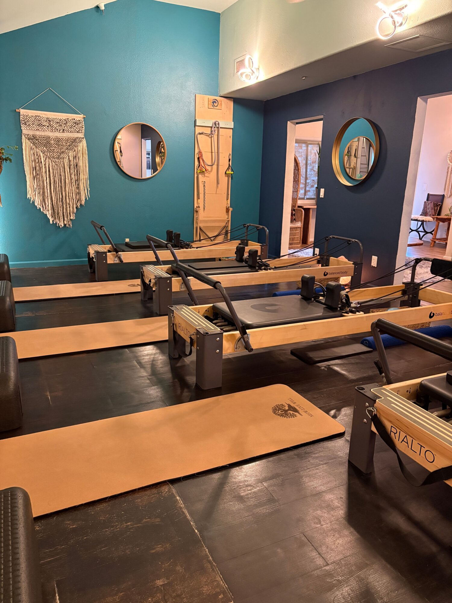 Workshop with workbenches, tools, and a teal wall with circular mirrors and a hanging textile piece.