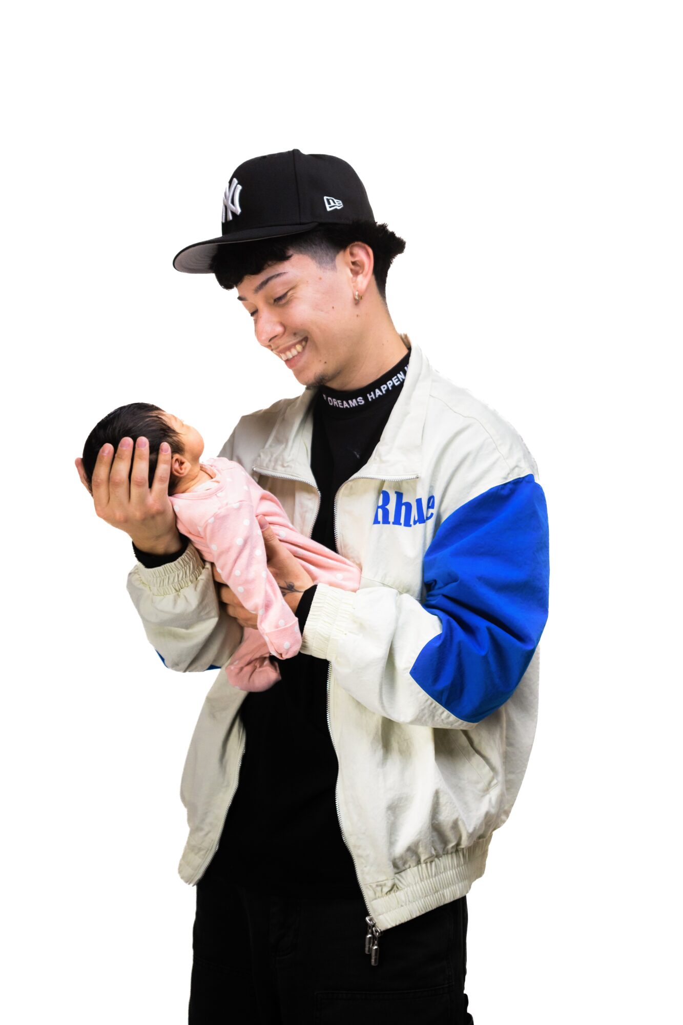 Young man smiling at a baby girl, holding her in his arms, against a white background.