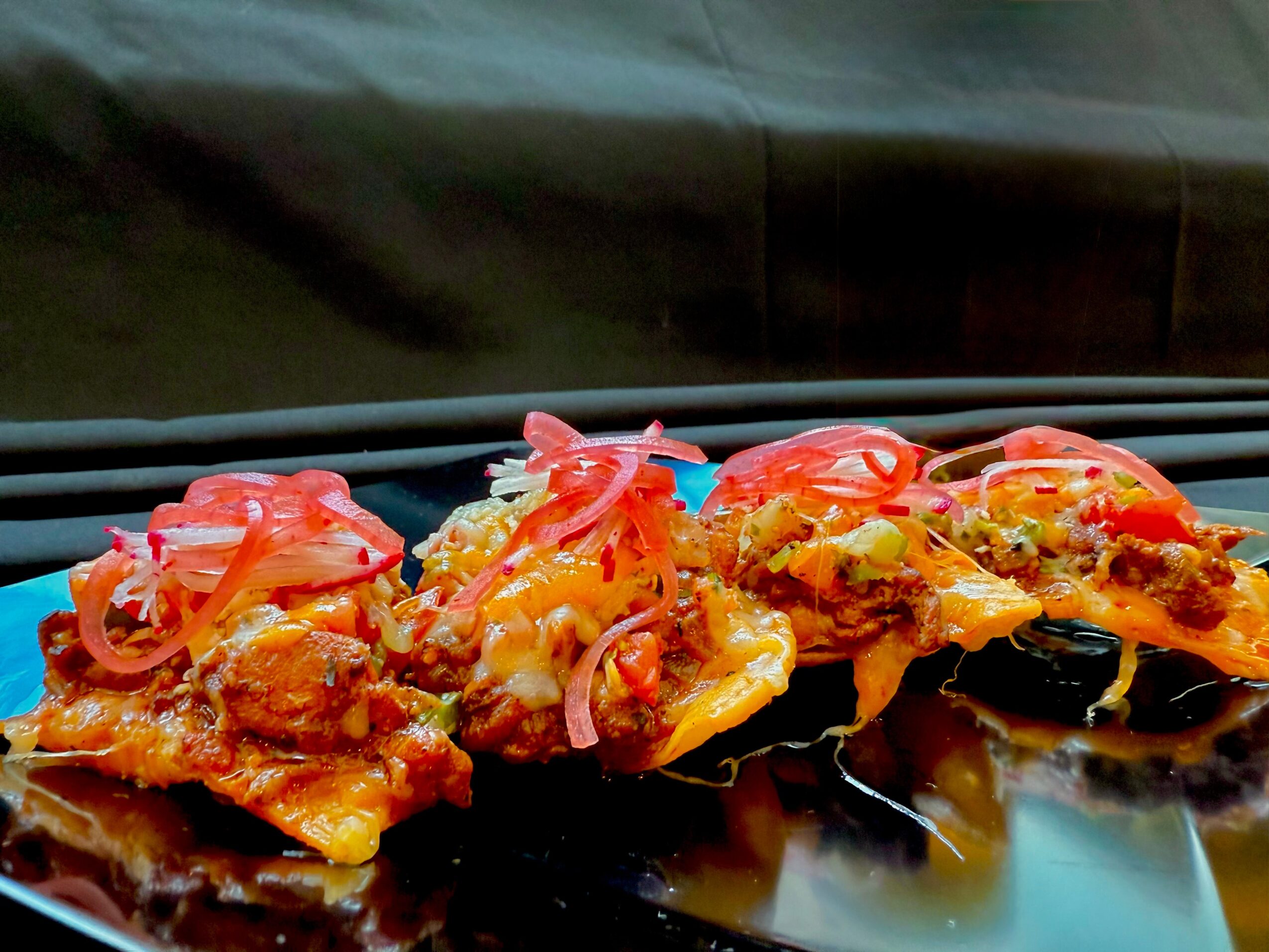 Three slices of pizza topped with vegetables and cheese on a black surface.