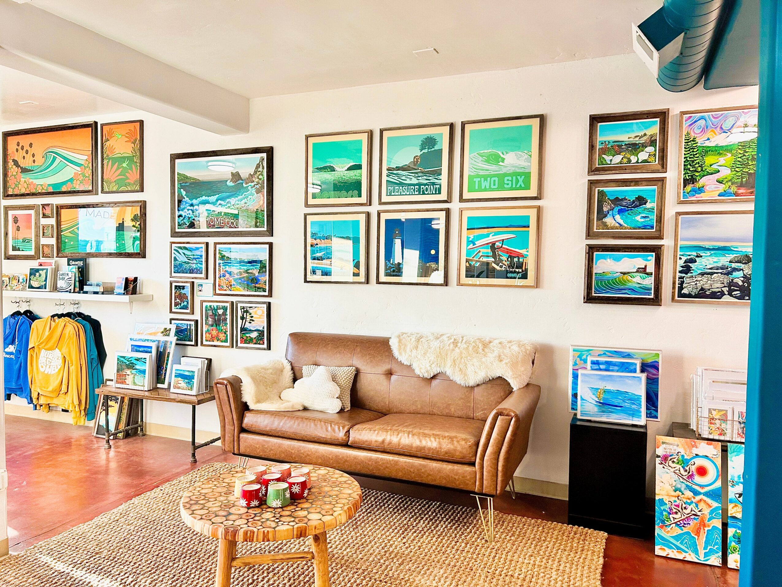 Living room with framed artwork on white walls, a brown sofa, a small round table, and various decorative items.