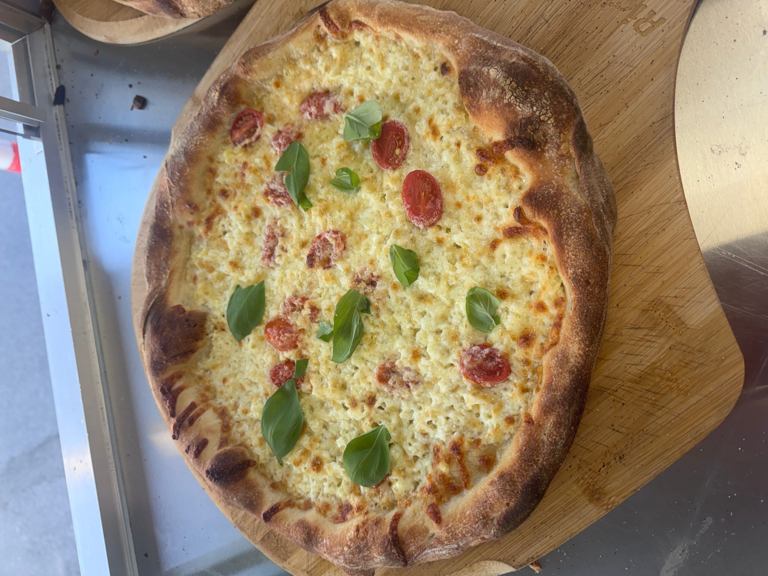 Pizza with cheese, pepperoni, and green leaves on a wooden surface.