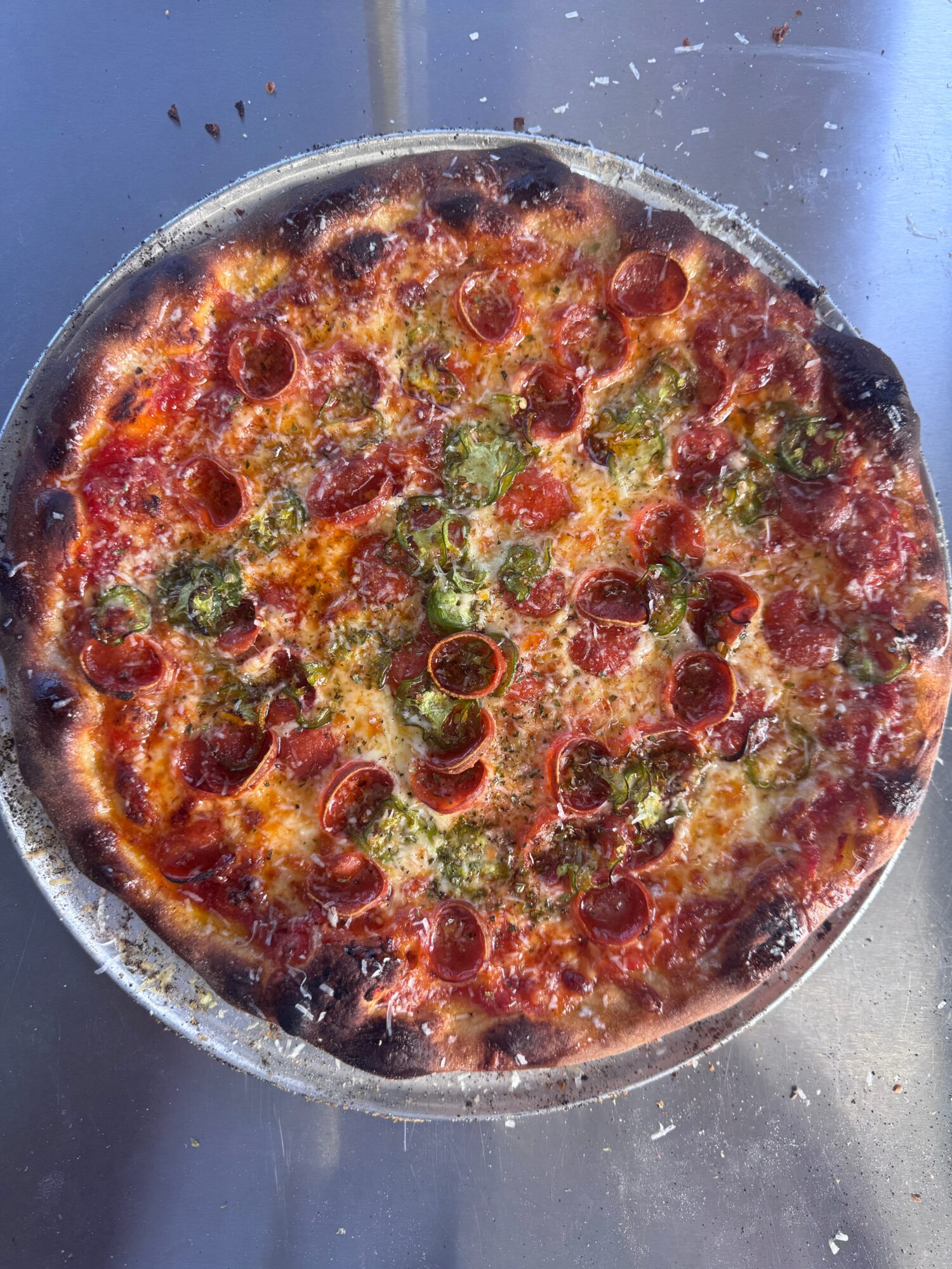 Pizza with pepperoni, green peppers, and melted cheese on a round crust, viewed from above.