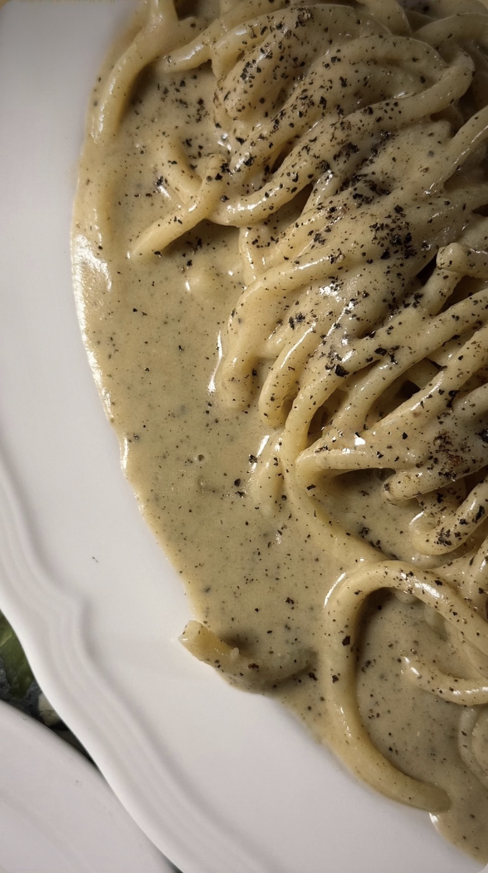 Close-up of creamy pasta with black pepper on a white plate.