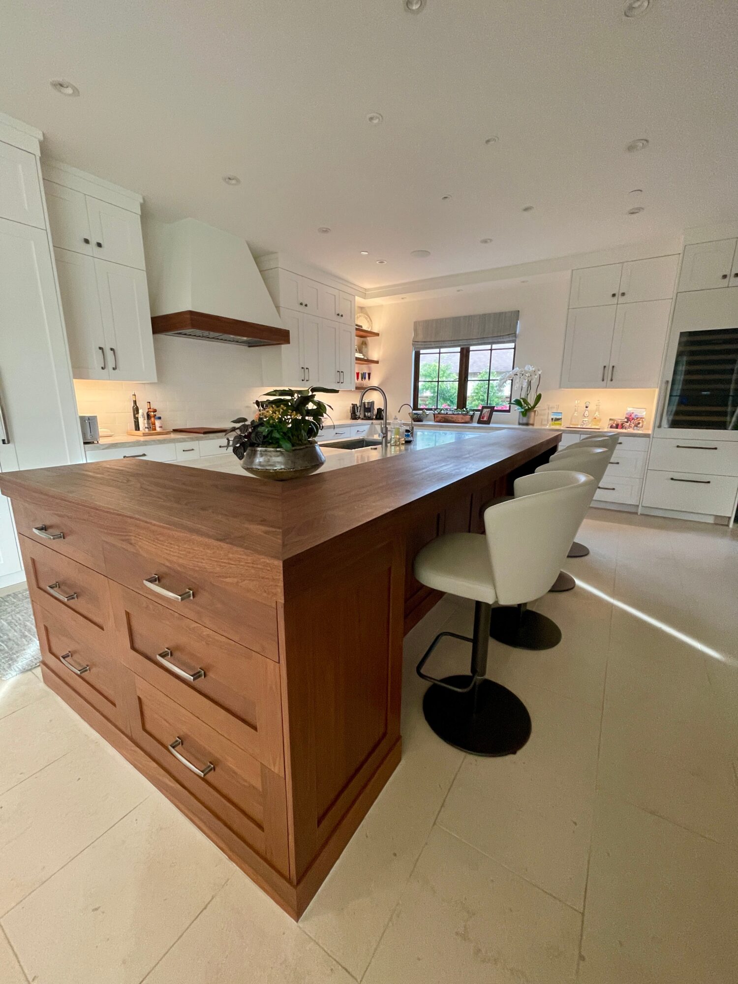Kitchen with a large wooden island, white cabinets, and a window with natural light.