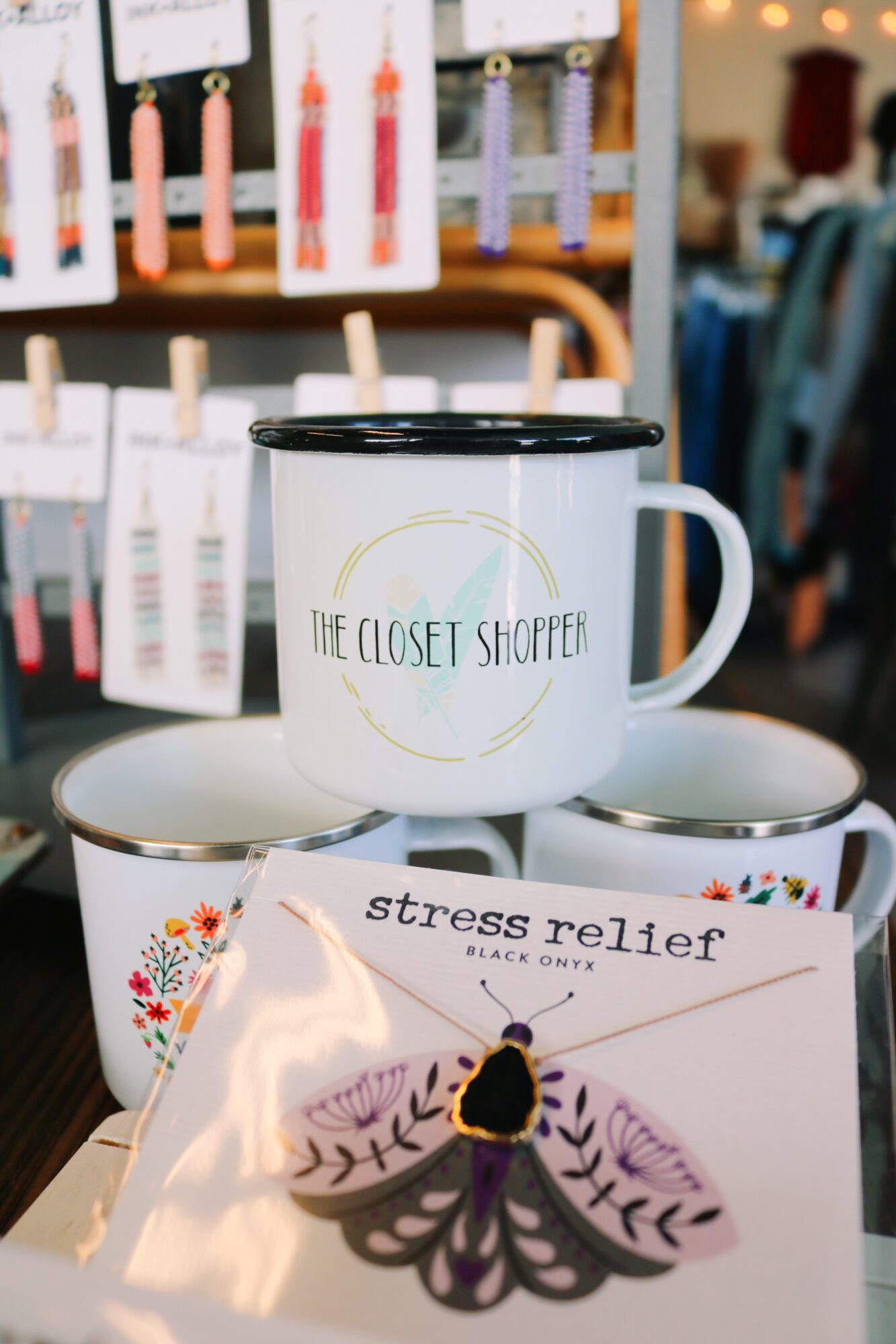 A white mug with black rim and logo, a magazine titled 'stress relief,' and a decorative butterfly on a store shelf.
