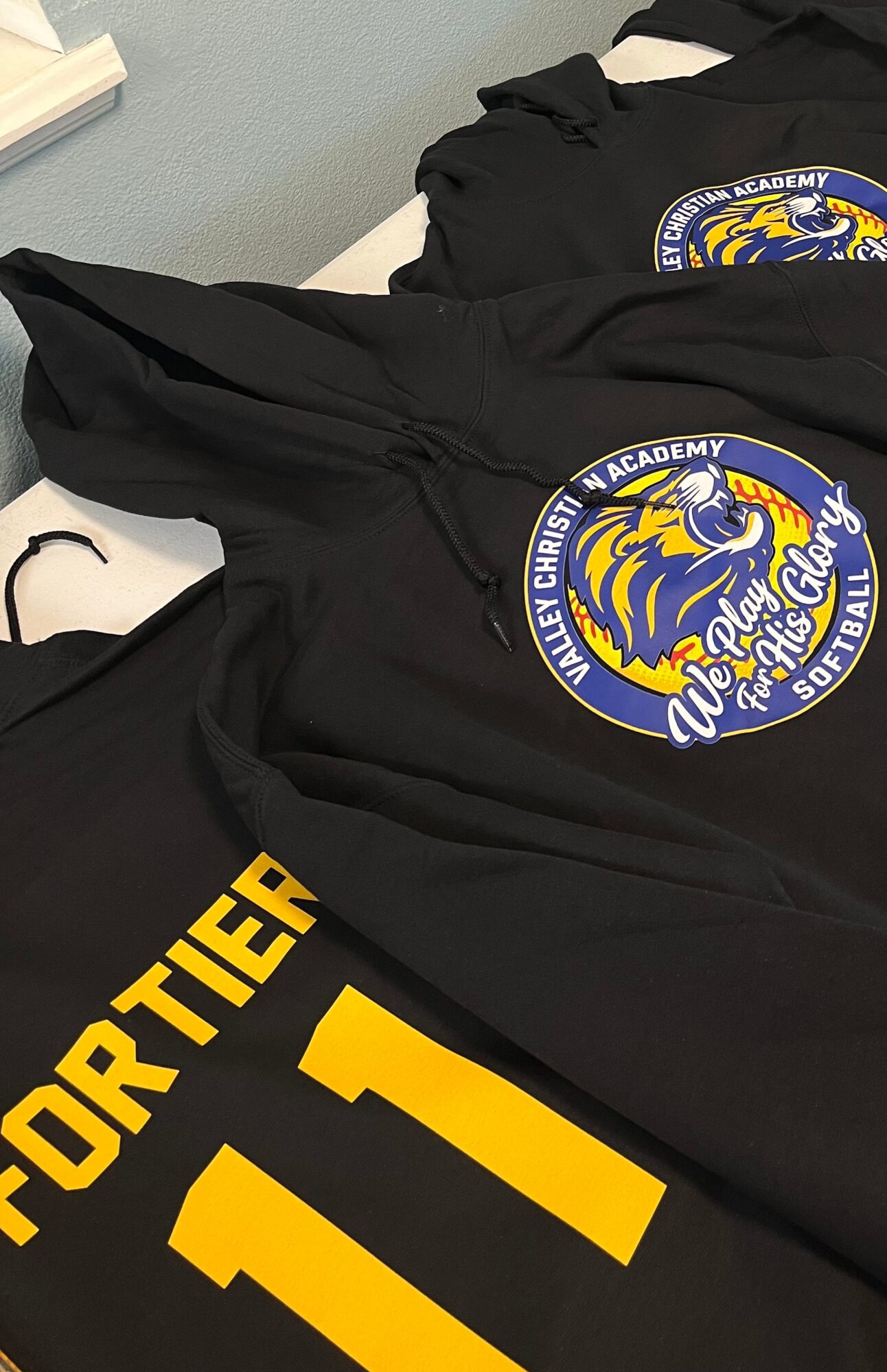 Black jackets with circular logo and yellow text, laid on a white surface, with a book partially visible in the top left corner.