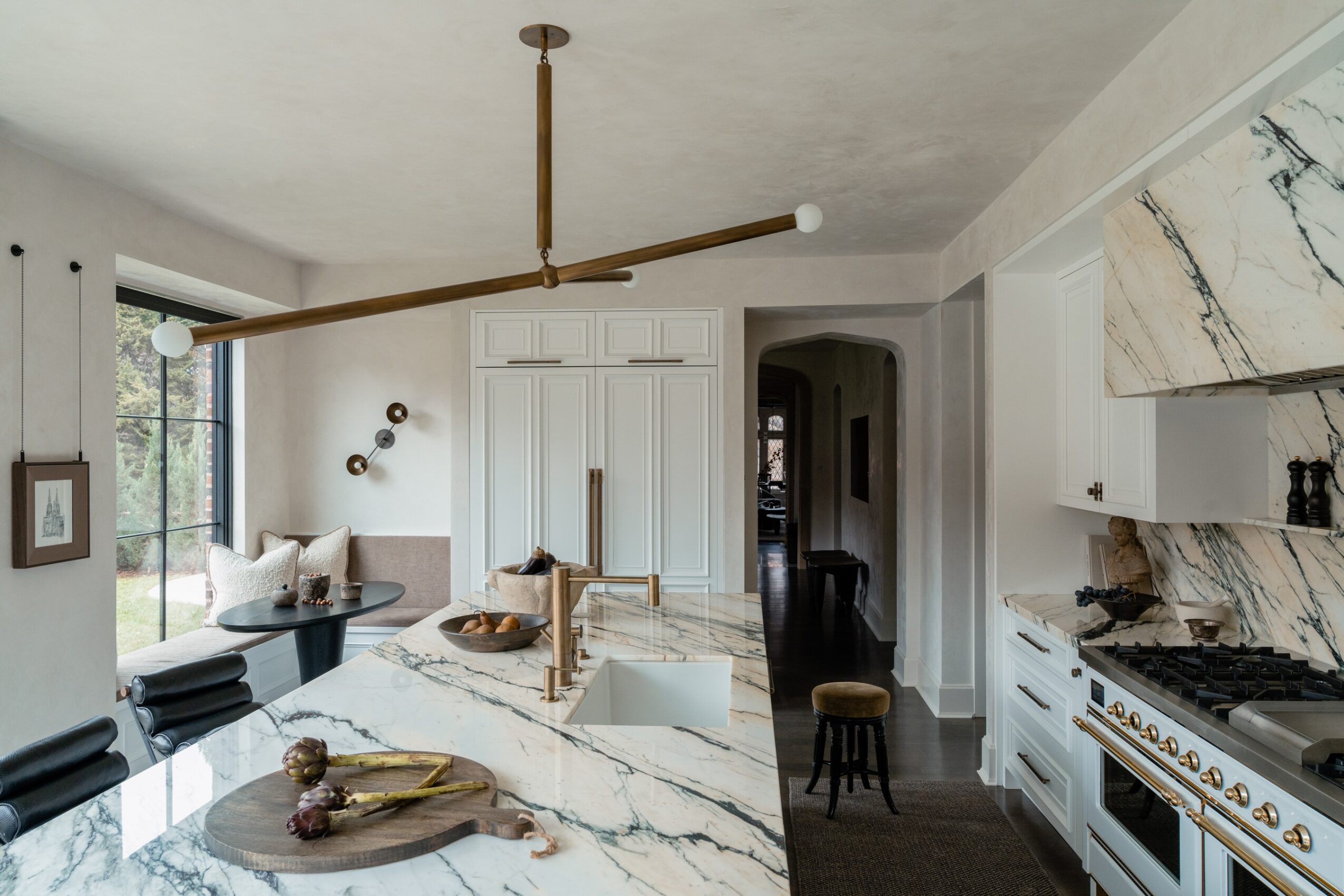 Modern kitchen with white marble countertops, a black dining table, and a unique wooden ceiling light fixture.