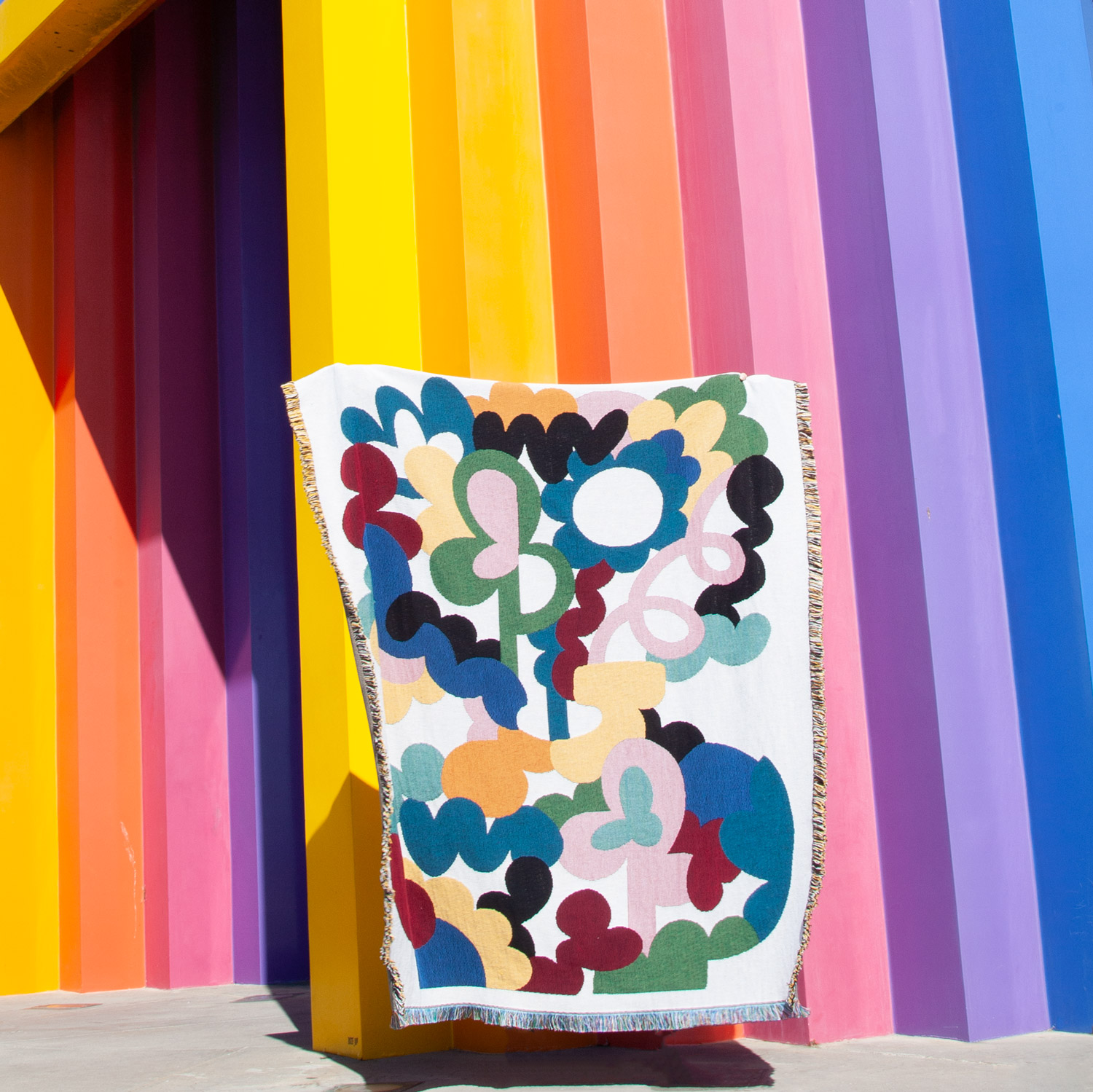 Colorful striped wall with a hanging textile featuring abstract shapes and patterns.