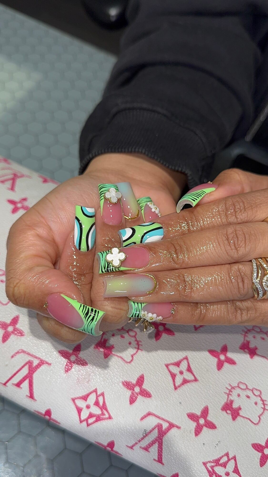 Close-up of a person's hand with decorated nails, resting on a pink and white patterned surface.