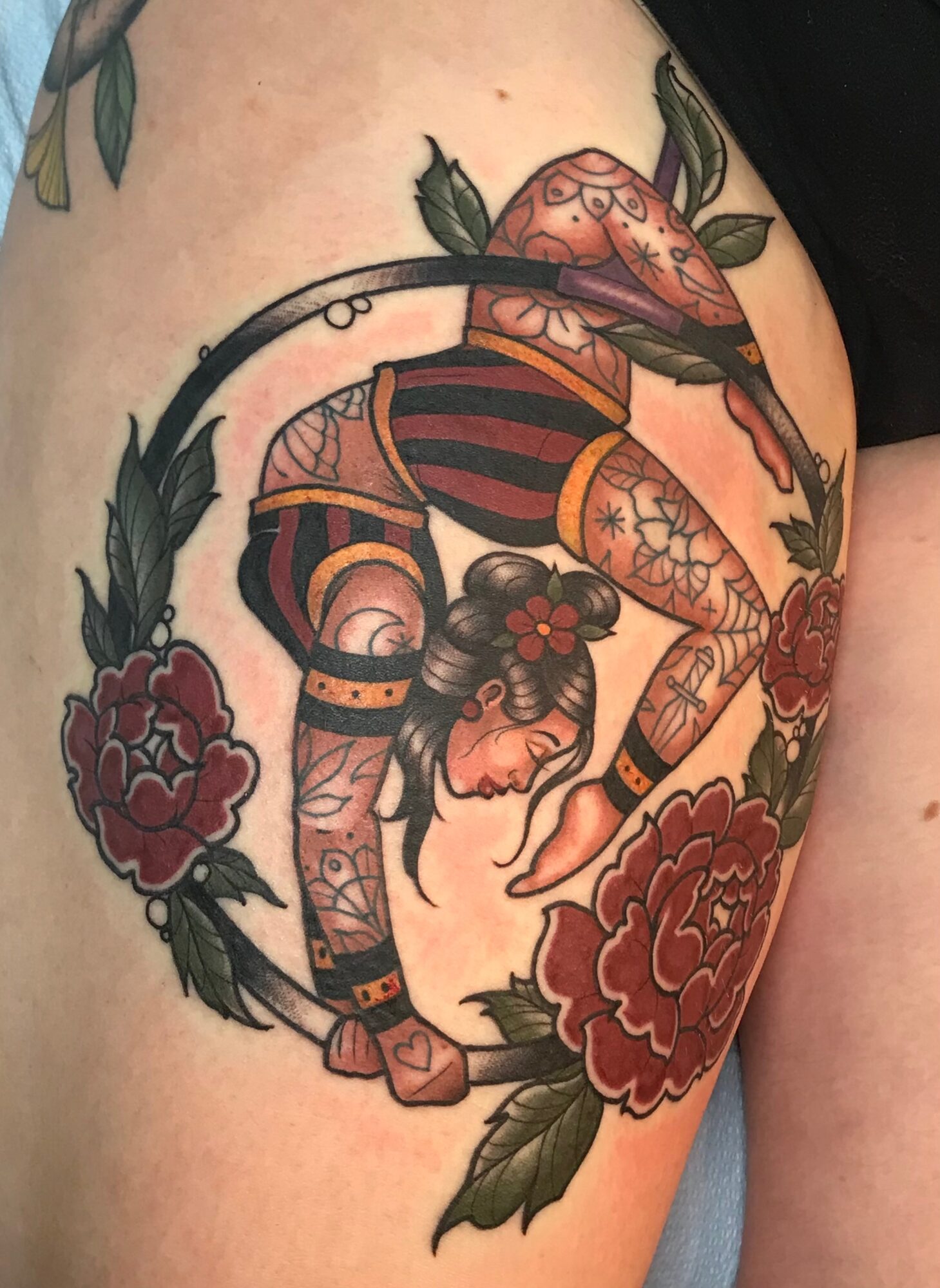 Tattoo of a woman with long hair, surrounded by flowers, in a traditional style, with bold lines and colors.