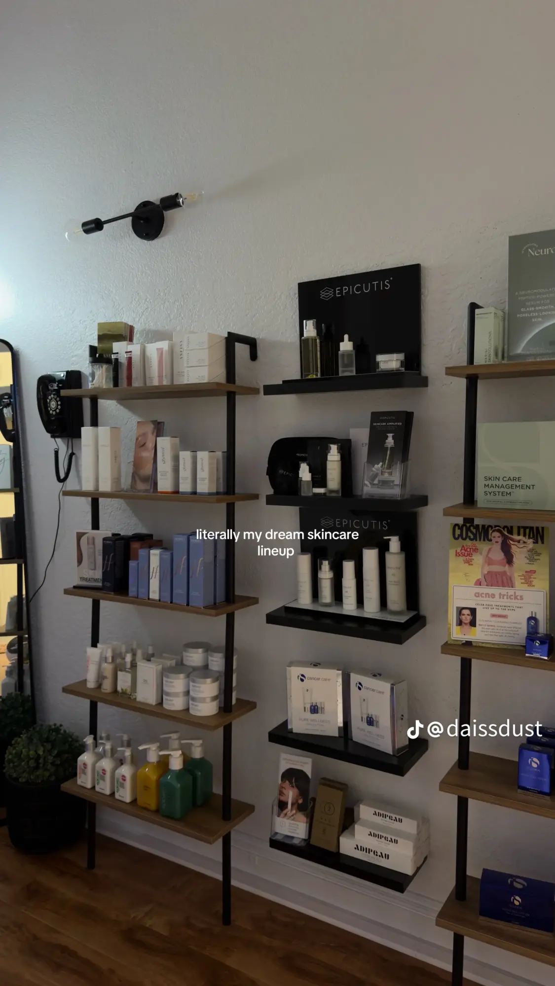 Wall-mounted shelves with skincare products, a mirror, and promotional materials in a store, with a wooden floor.