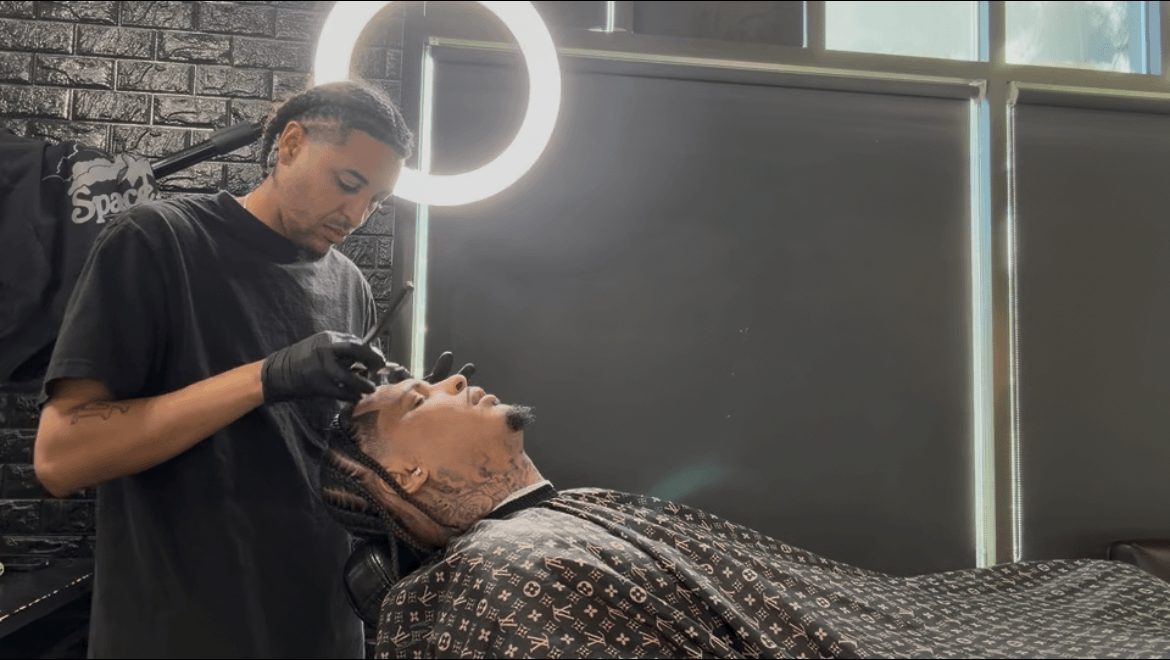 Person receiving a facial treatment from a professional in a modern salon, with a ring light in the background.