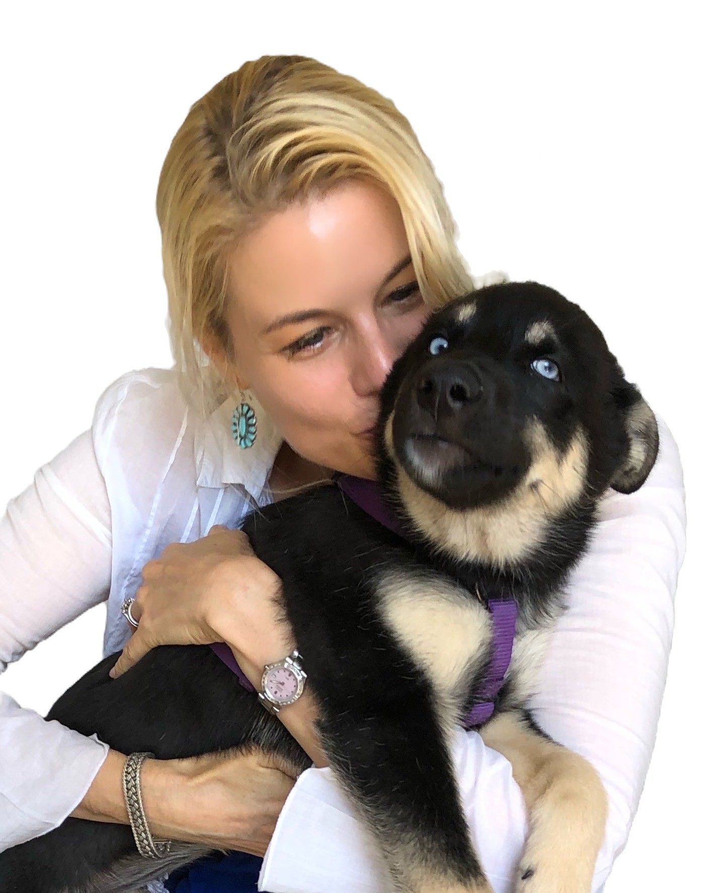 Woman with blonde hair hugging a black and tan puppy with blue eyes, both smiling, against a white background.