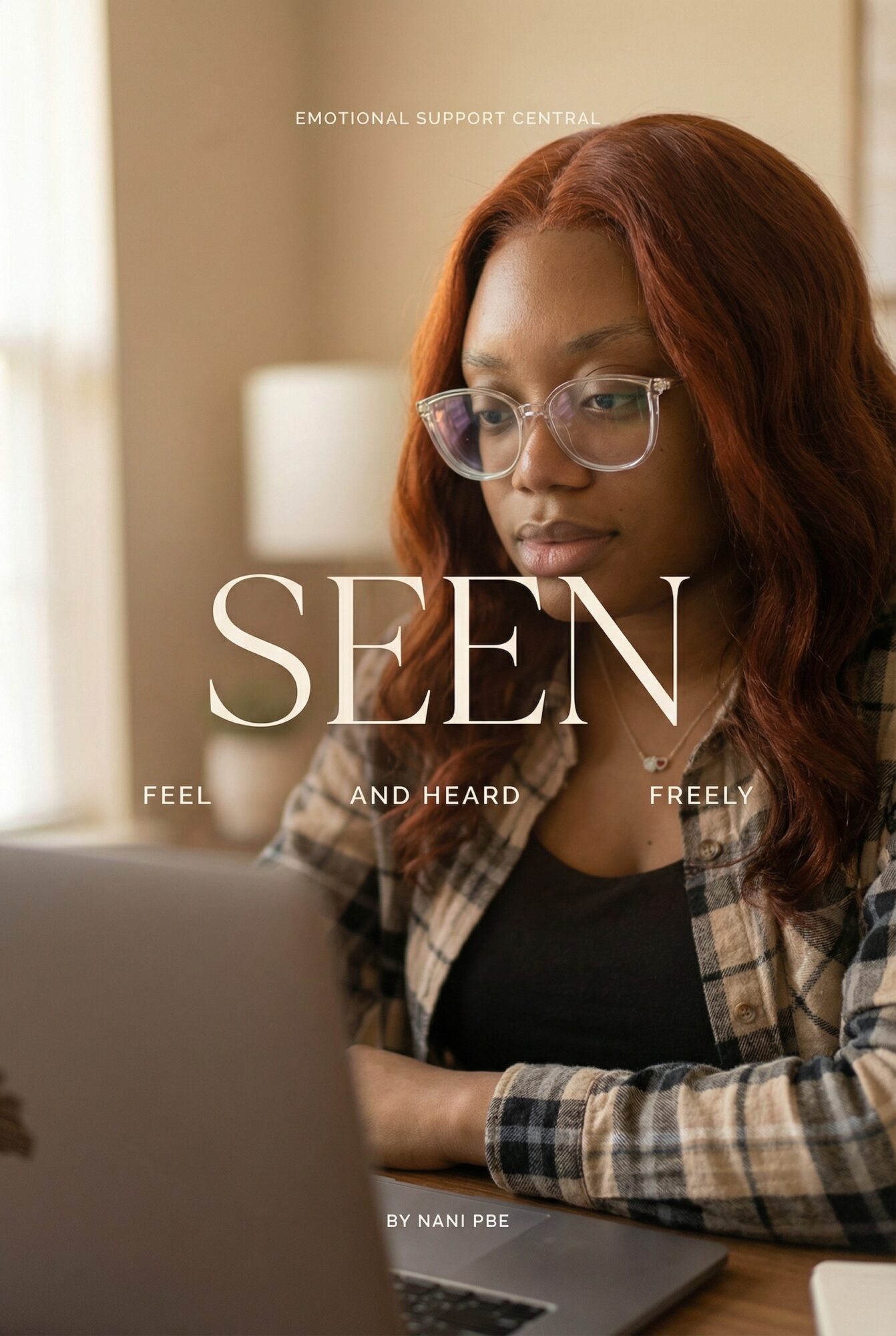 Woman with red hair and glasses working on a laptop indoors, focused on screen.