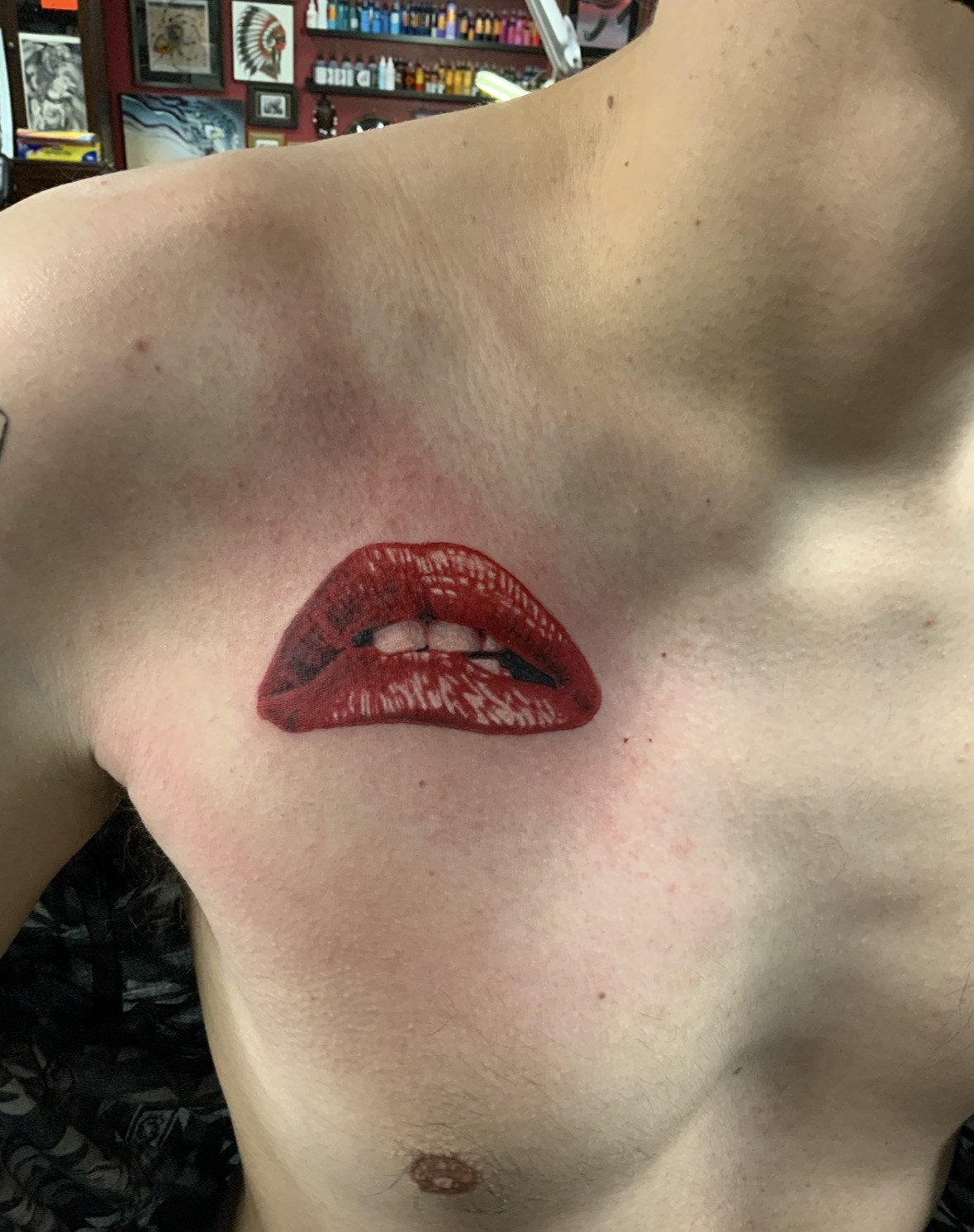 Close-up of a person's shoulder and chest with painted lips on the skin, in a store setting.