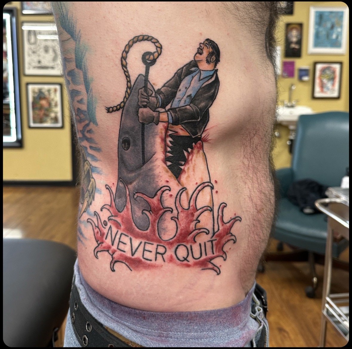 Tattoo of a person with a mask holding a large key, with flames and the words 'NEVER QUIT' below.