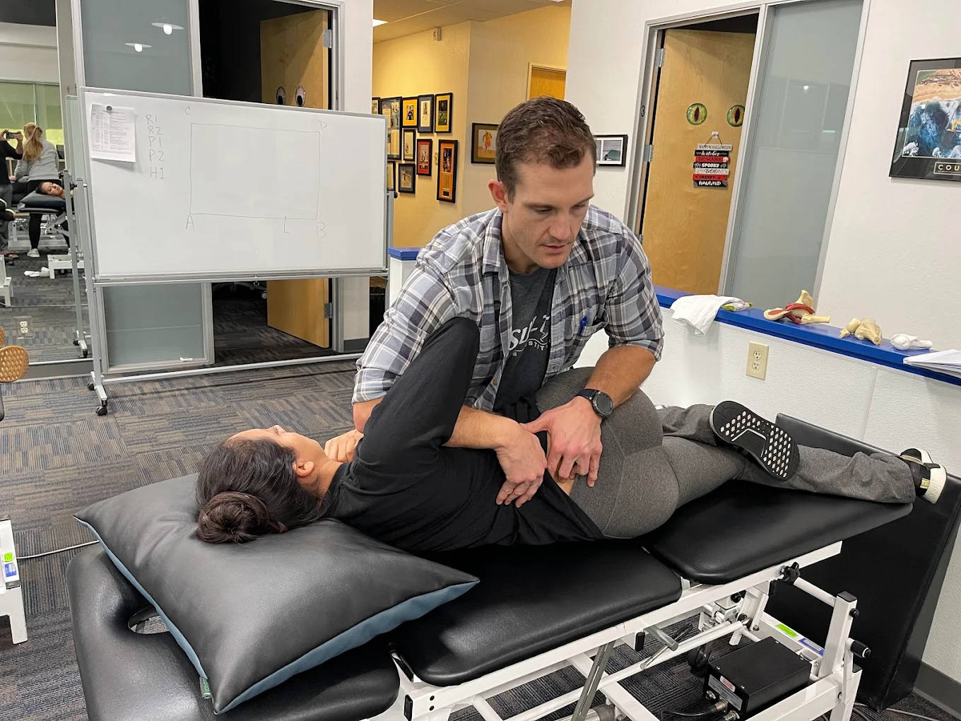 Man providing chiropractic adjustment to a woman lying face down on a treatment table in an office setting.