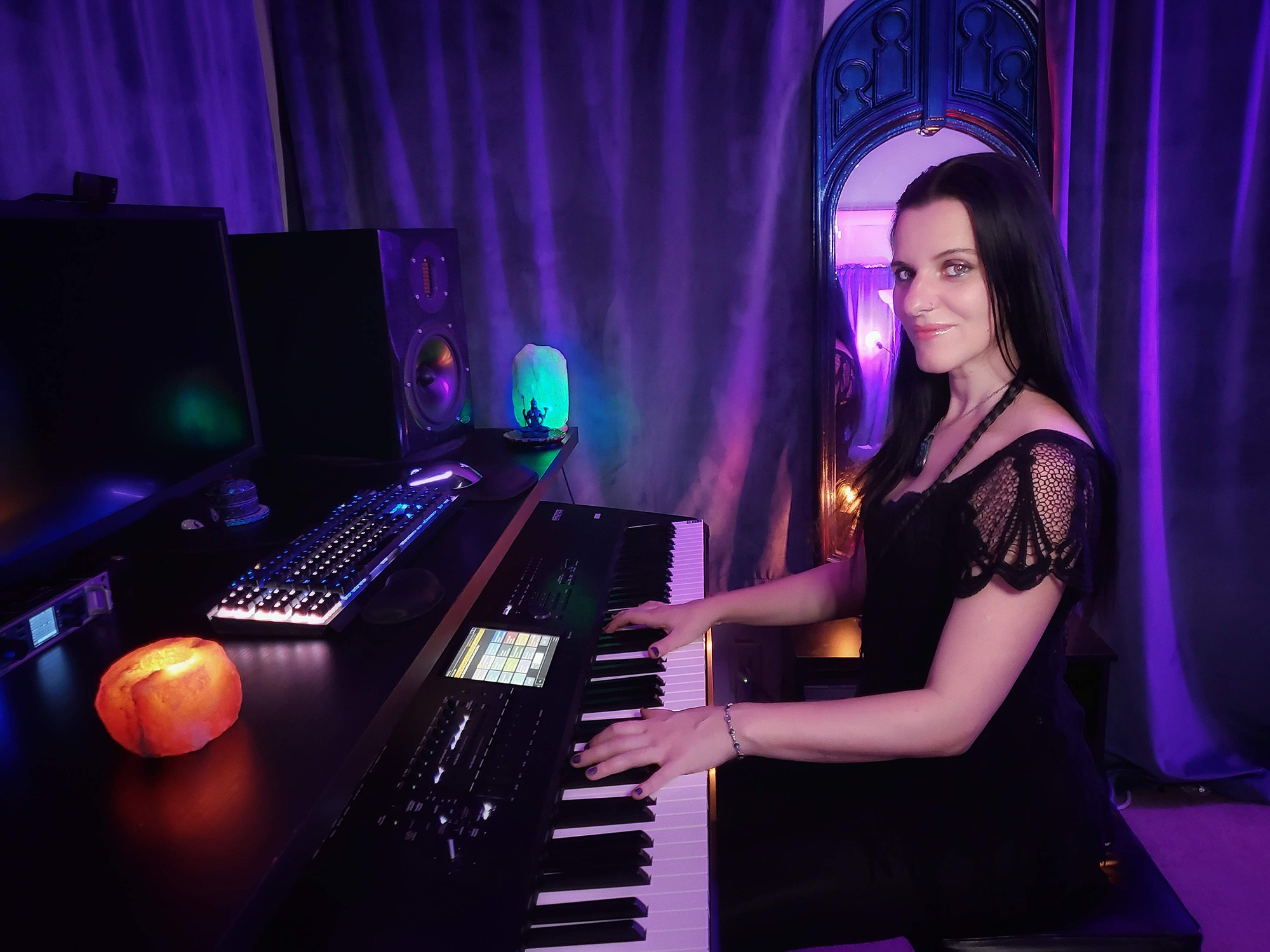 Woman playing keyboard in a room with purple curtains and colorful lighting, with a pumpkin on the desk.