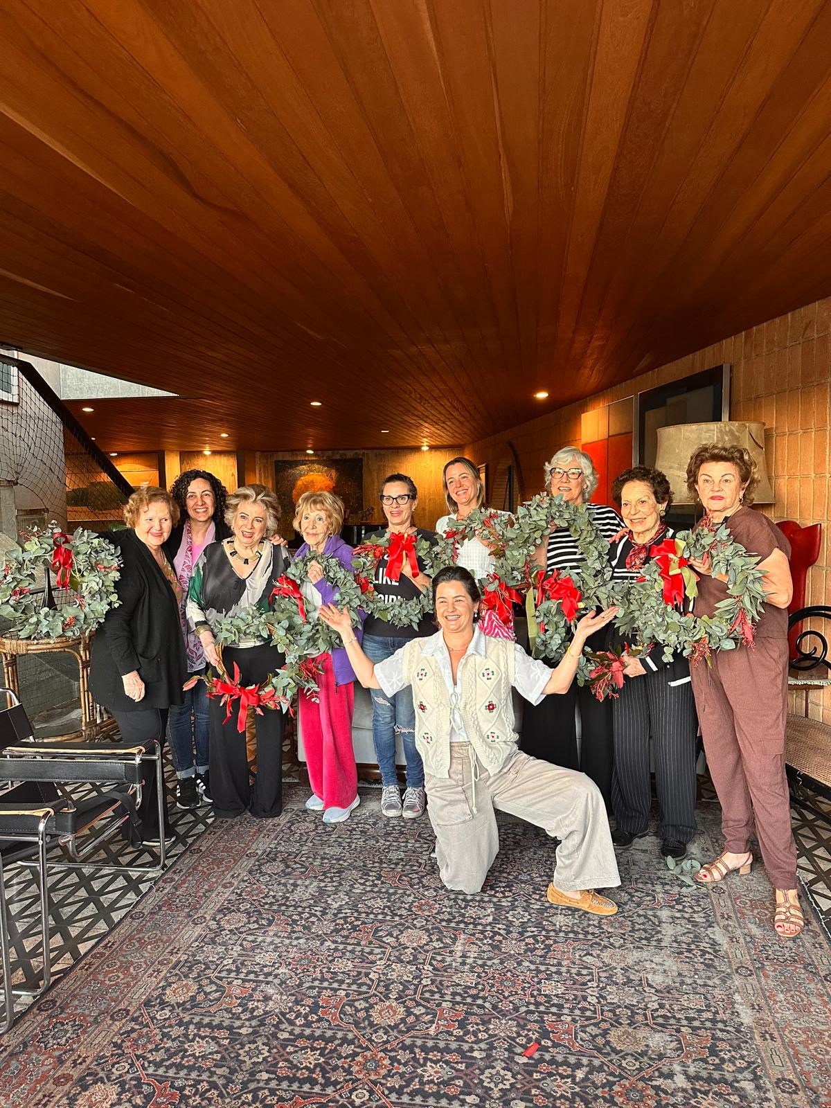 Group of people holding large bouquets of flowers in a room with wooden ceiling and patterned carpet.