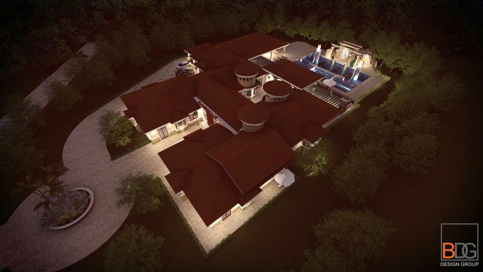 Aerial view of a large house with a swimming pool, surrounded by trees and a curved driveway.