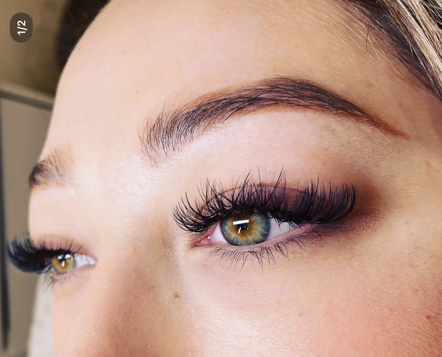 Close-up of a person's eye with makeup, including long eyelashes and well-groomed eyebrow.