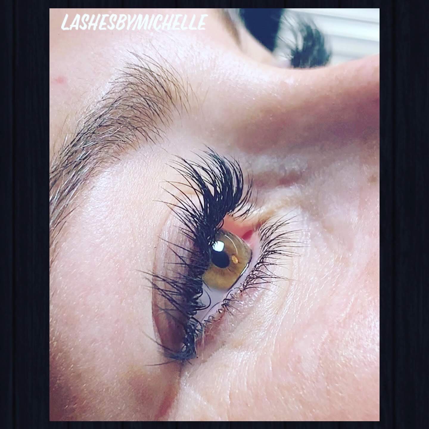 Close-up of a person's eye with long, curled eyelashes and well-groomed eyebrow, looking upward.