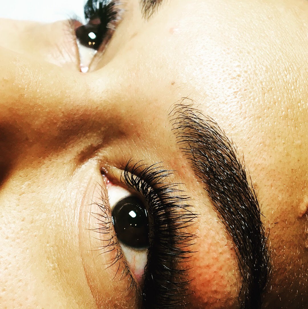 Close-up of a person's eye with long eyelashes and well-defined eyebrow, looking slightly upward.