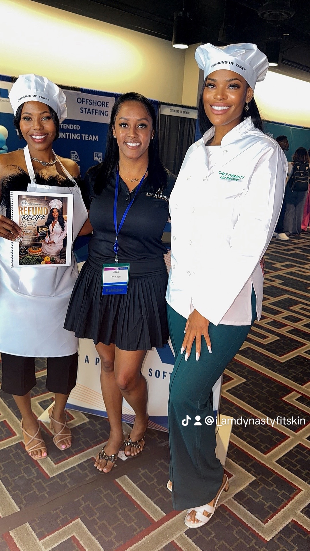 Three women standing together indoors, two in chef uniforms and one in casual attire, smiling at the camera.
