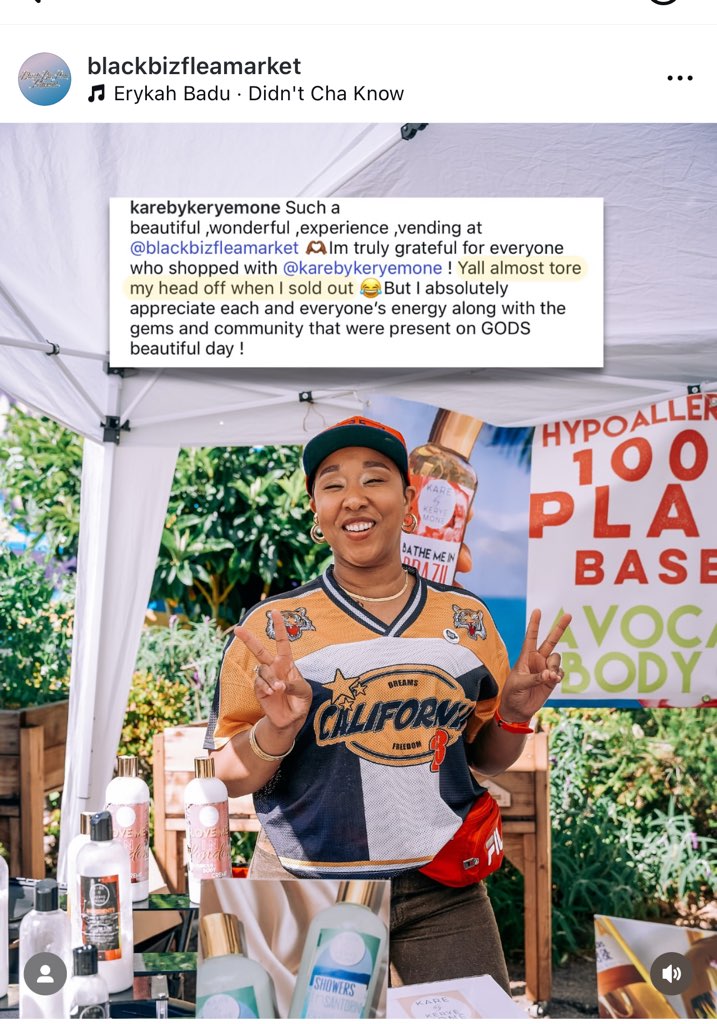 Smiling person wearing a California-themed shirt and cap, standing outdoors with a sign and products displayed around.