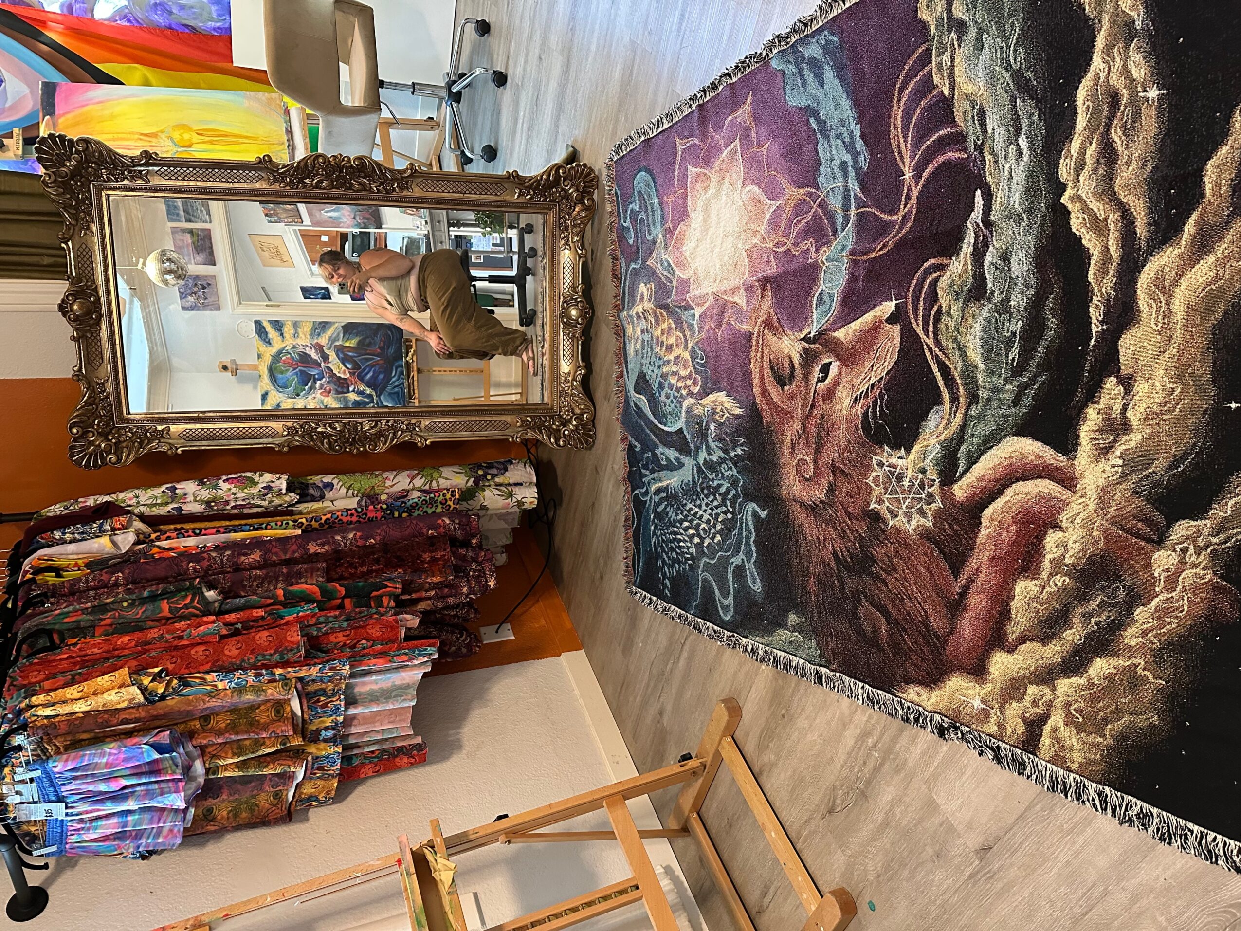 Decorative rug with a mythological scene, ornate mirror, and colorful fabric curtains in a room.