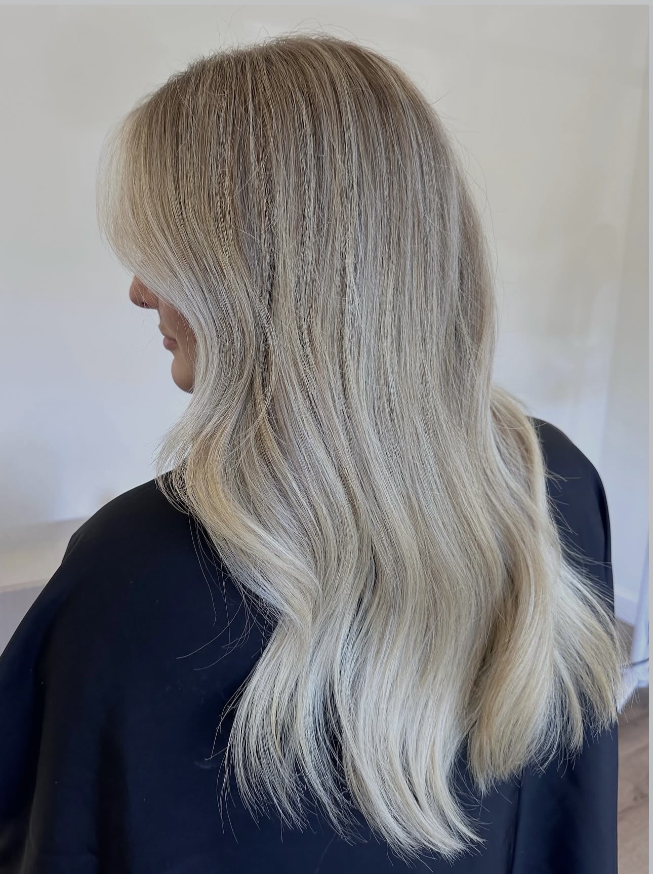 Side view of a person with long, wavy blonde hair wearing a dark top.