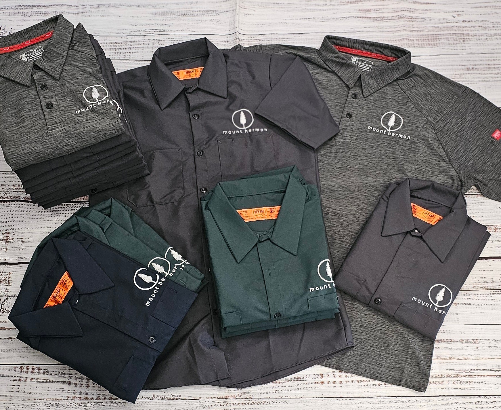 Collection of polo shirts in various colors with logo, arranged on a light wooden surface.