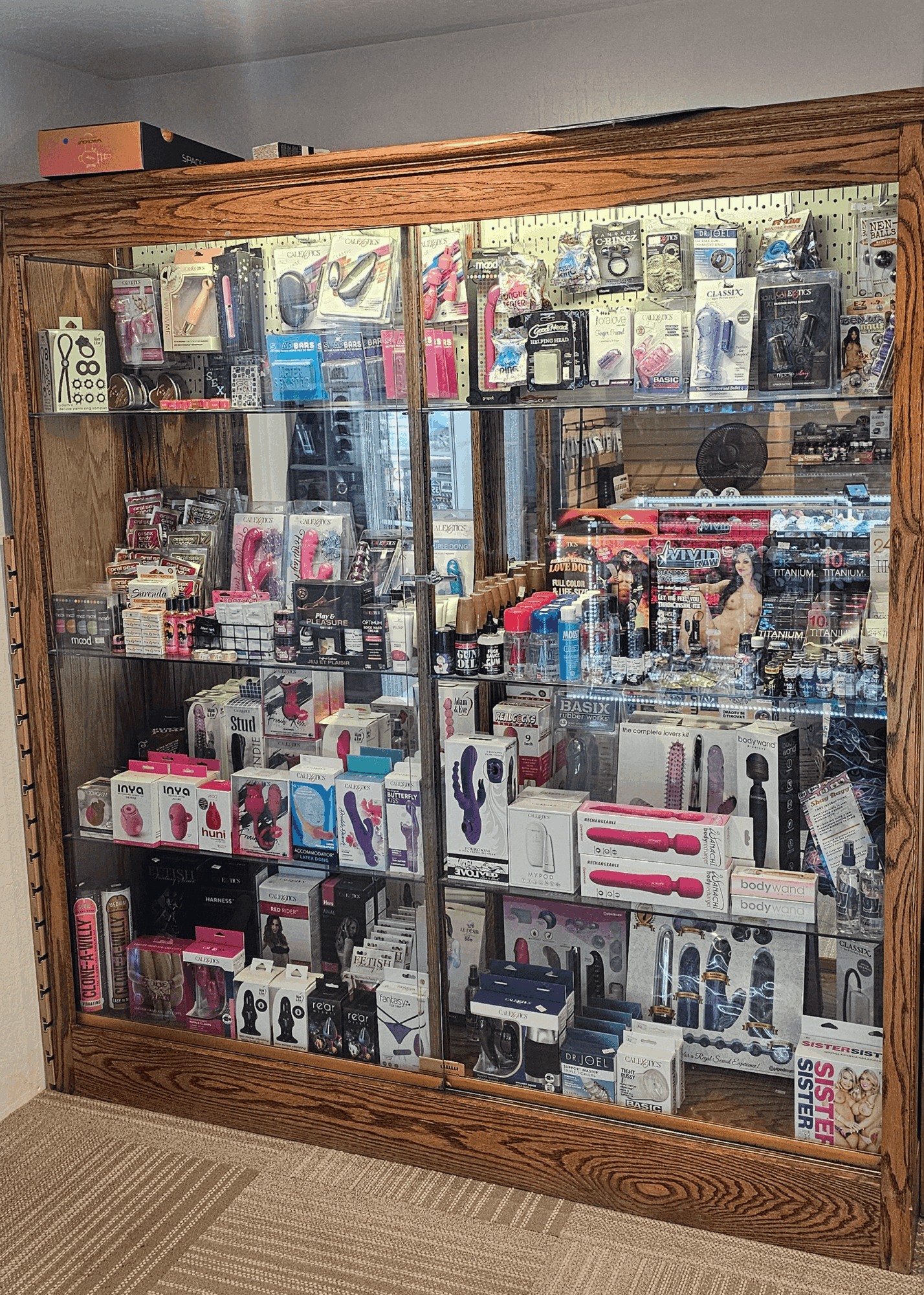 Display case filled with various electronic accessories and gadgets, glass front, wooden frame, located indoors.