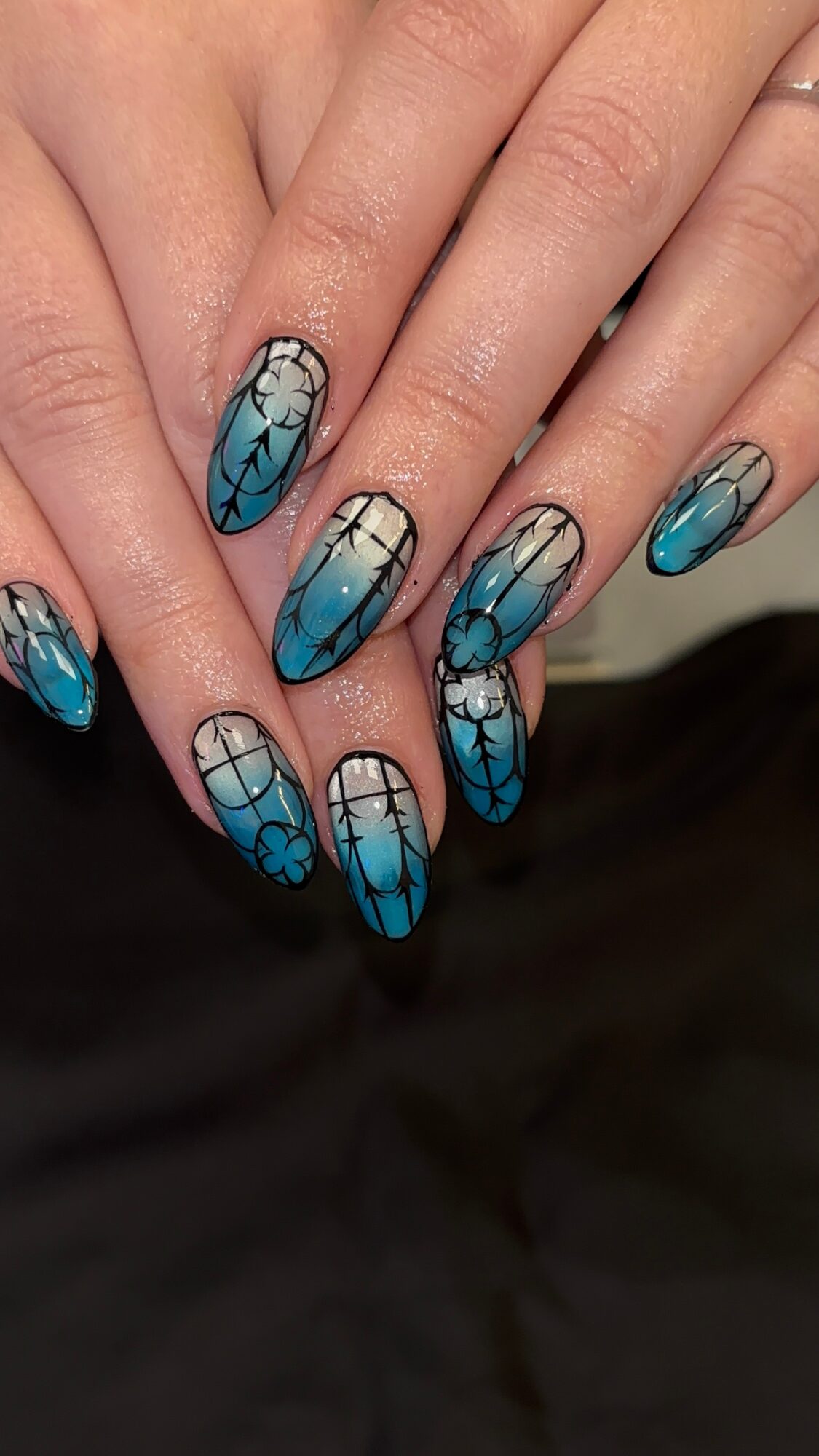 Nail art with blue, black, and white geometric and cracked patterns on long nails.