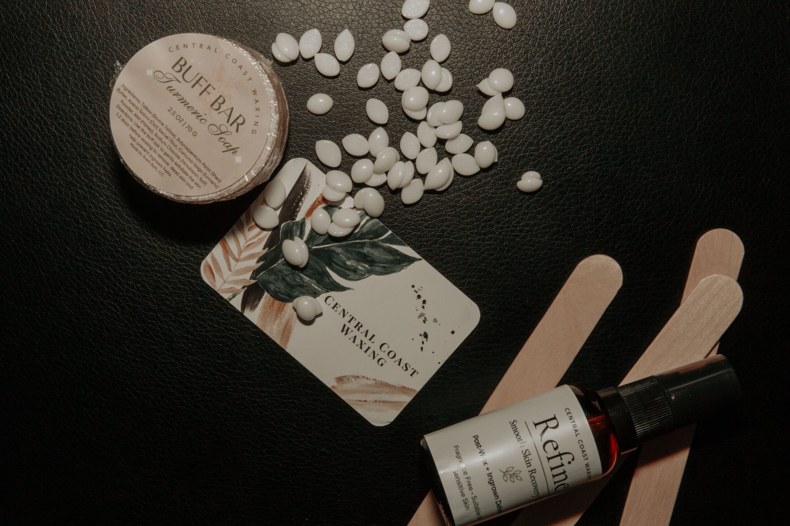Small container, scattered white pills, a card with a bird illustration, and a dropper bottle on a dark surface.