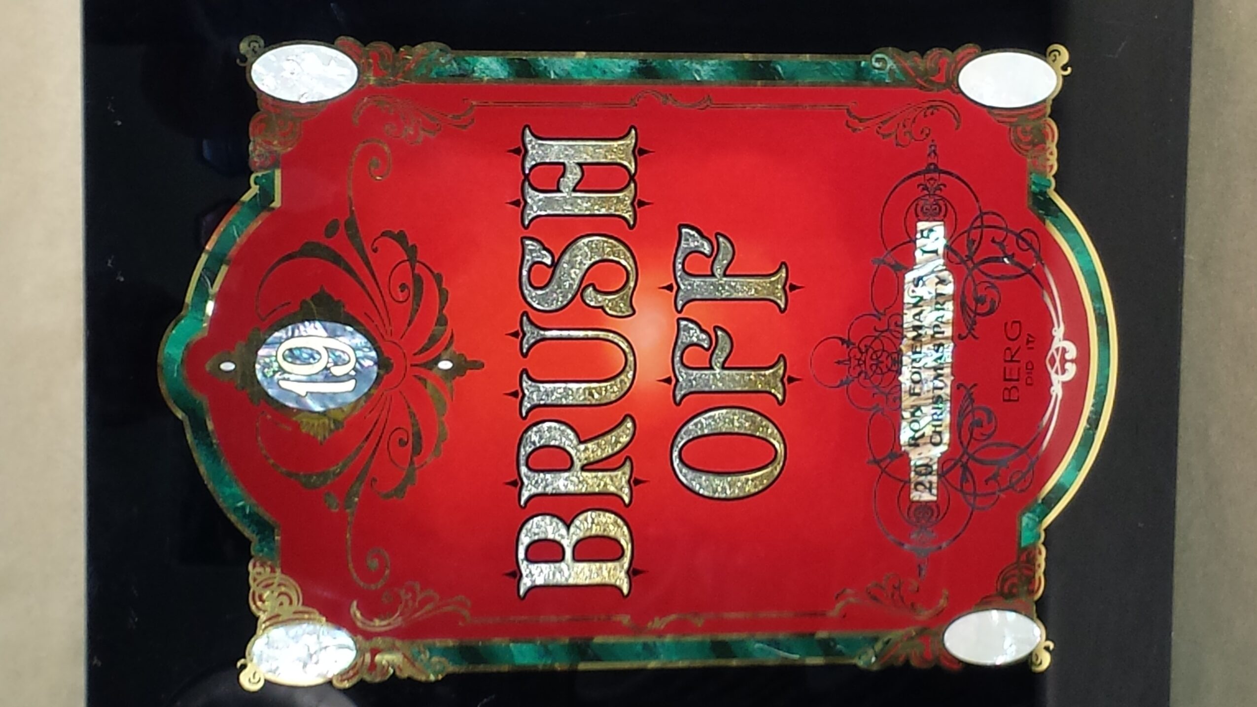 Red and green sign with ornate design, reading 'BRUSH OFF' in large letters, with additional text and decorative elements.