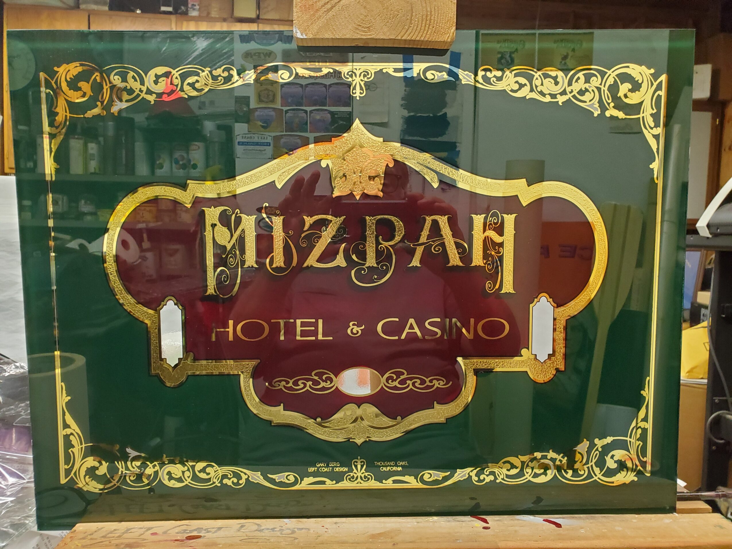 Sign for Mizban Hotel & Casino with ornate gold border and red and gold text on a green background.