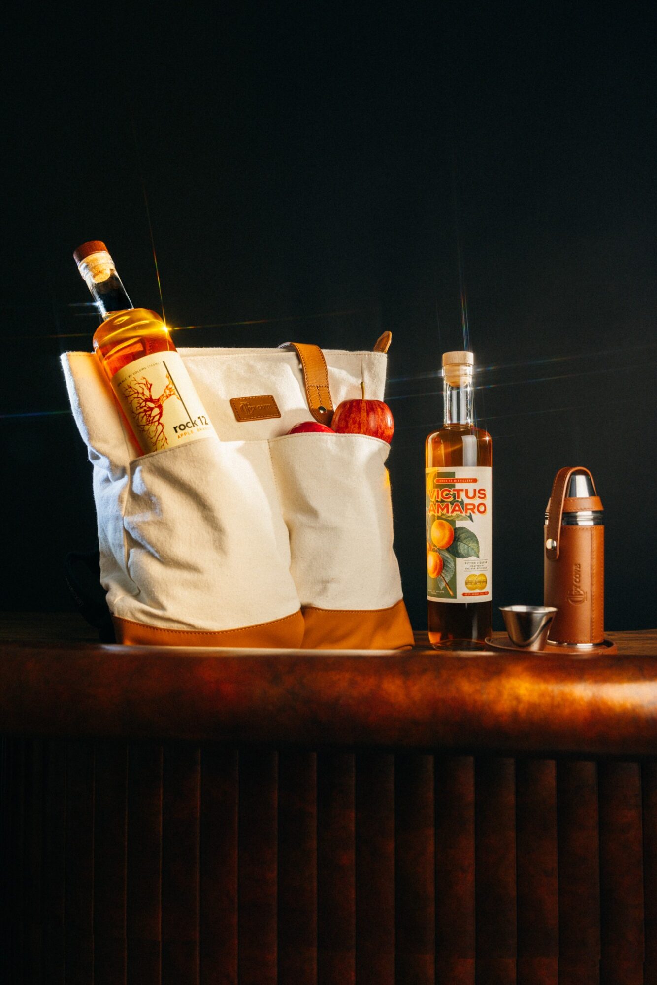 Bag with bottles and a thermos on a wooden surface against a dark background.