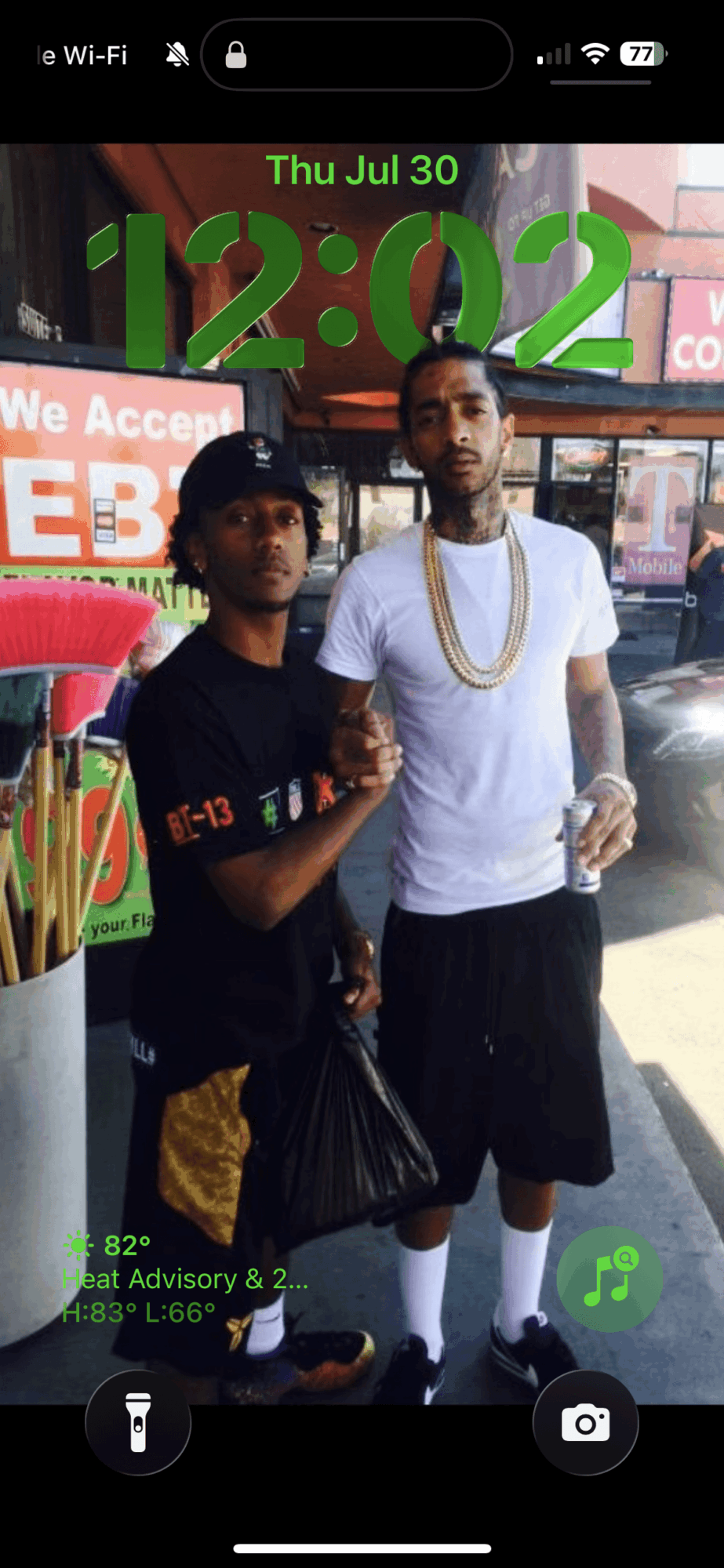 Two young men standing outdoors in front of a store, one holding a drink, both looking at the camera.