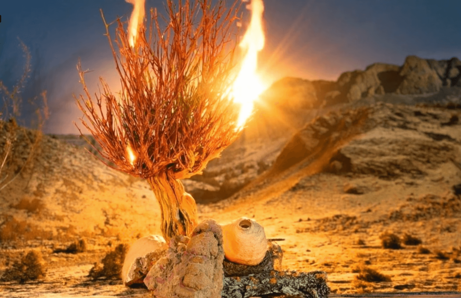 A desert landscape with a burning bush and rocky terrain under a clear sky.